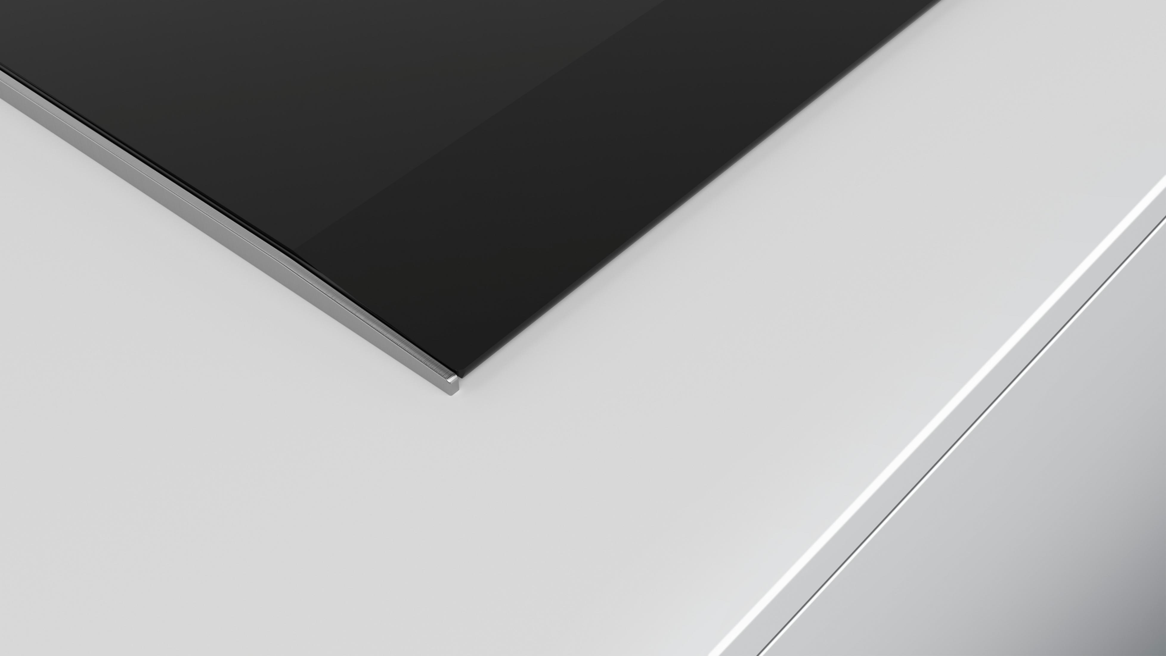 Zbliżenie czarnej płyty grzewczej z srebrną ramką na białym tle.