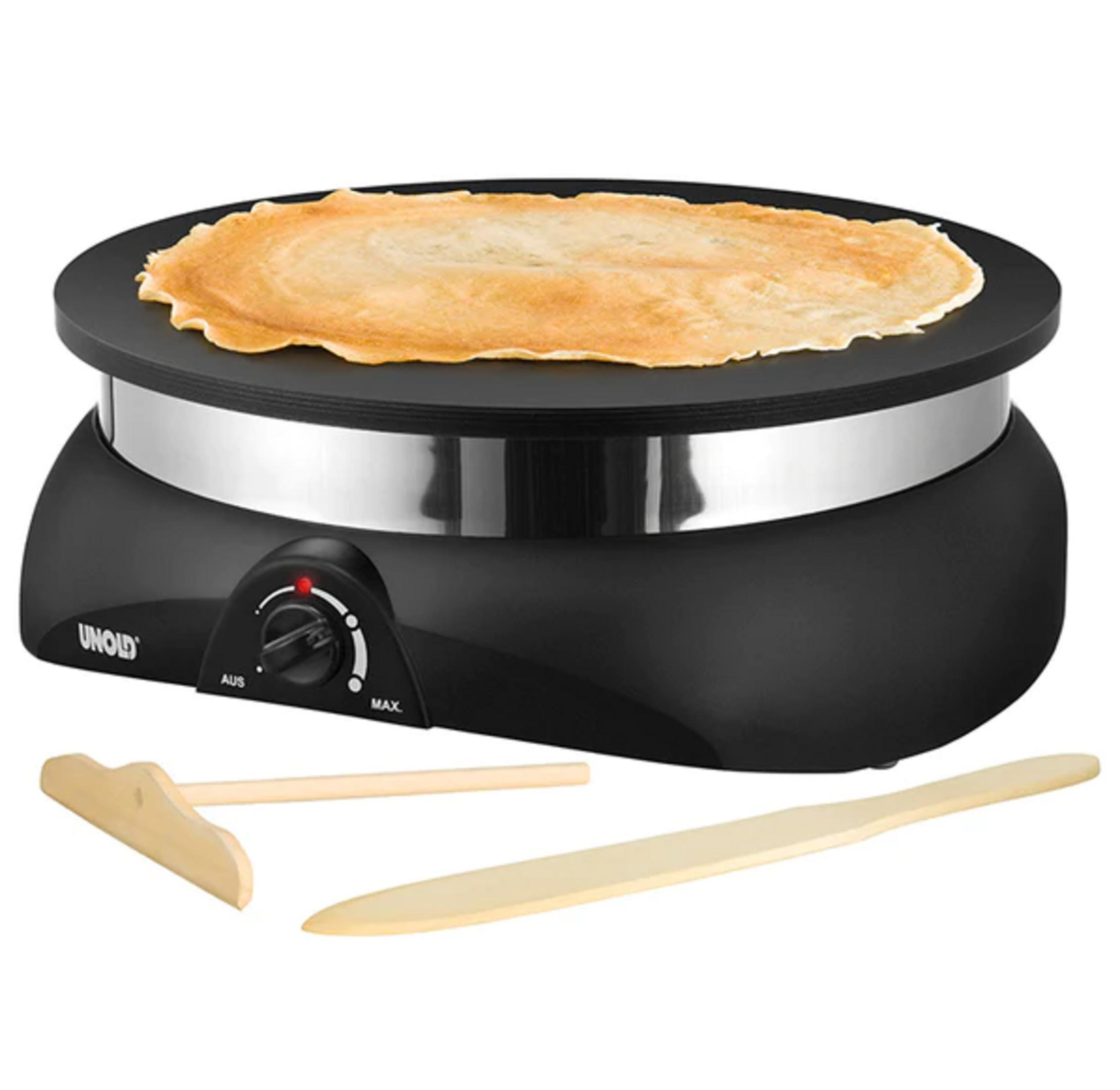 Una piastra per crepes nera con una crepe e attrezzi in legno.