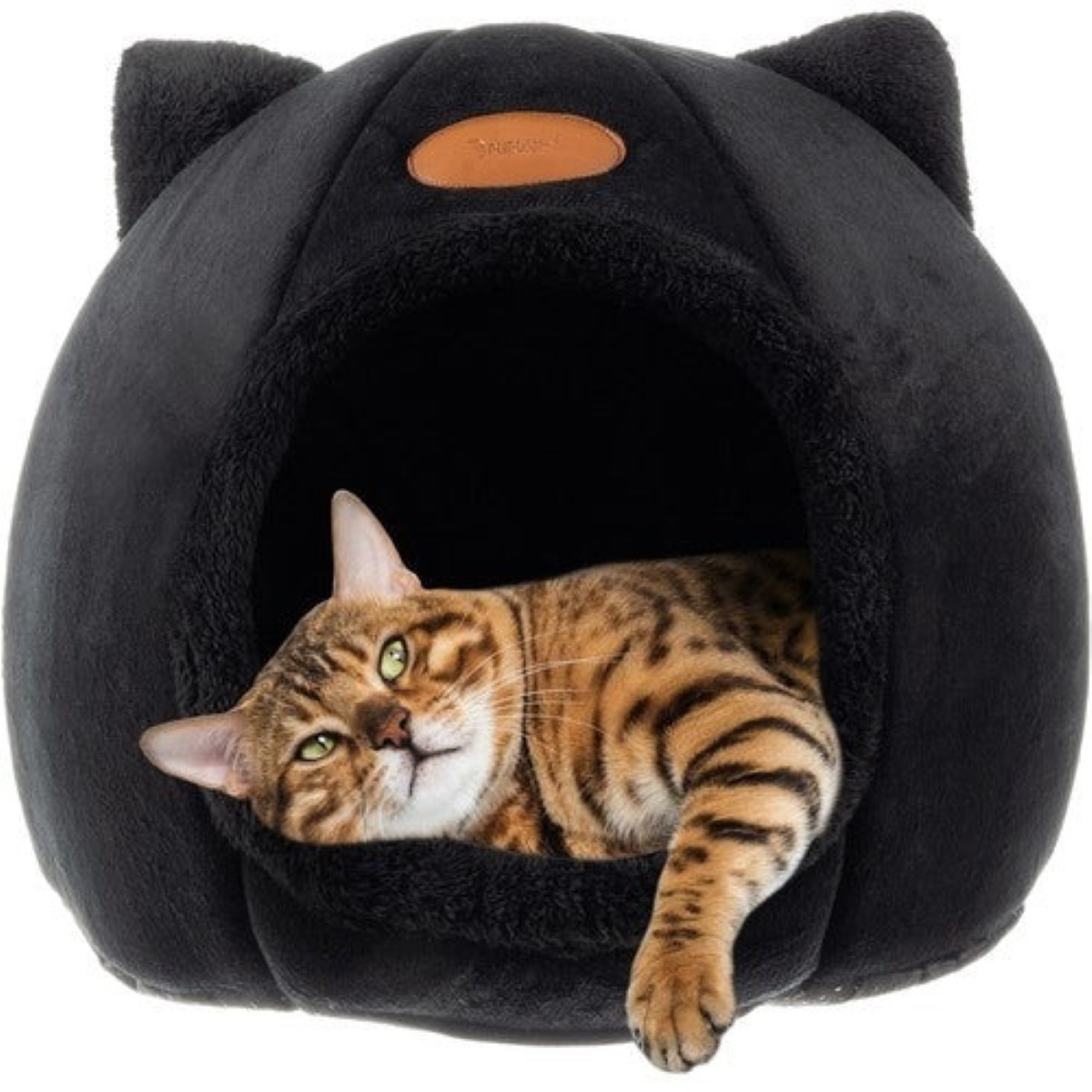 Un gato atigrado marrón yace en una cama negra para gatos con orejas.