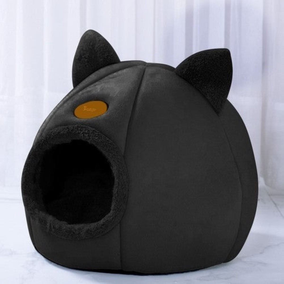 Cama negra con forma de gato con orejas y entrada redonda.