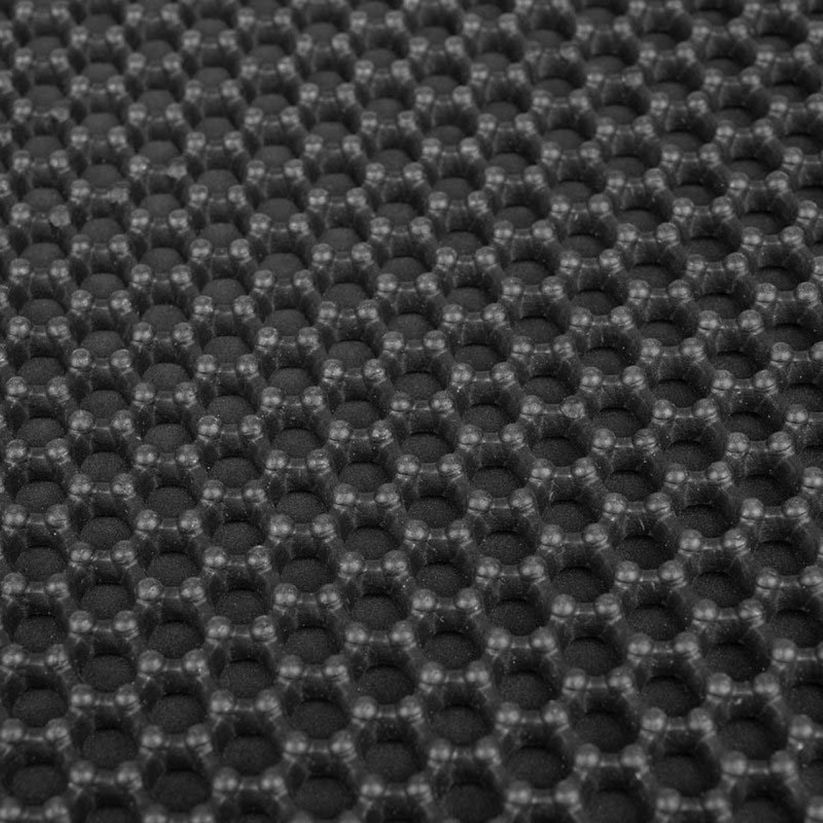 Rejilla de panal negra con celdas hexagonales y bordes elevados.