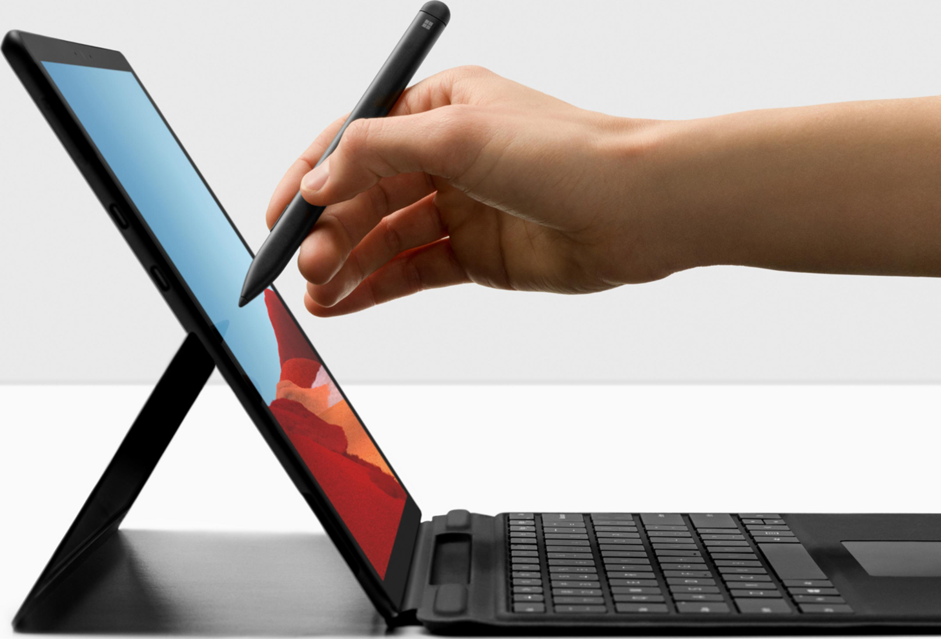 Una mano usa uno stilo nero su un laptop nero con tastiera.