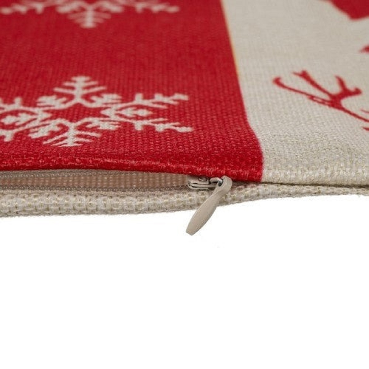 Cremallera blanca en un cojín con copos de nieve rojos y renos.