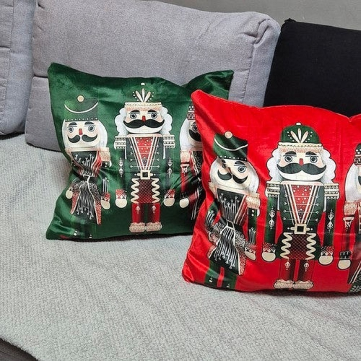 Cojines verdes y rojos con diseños de cascanueces en un sofá gris.