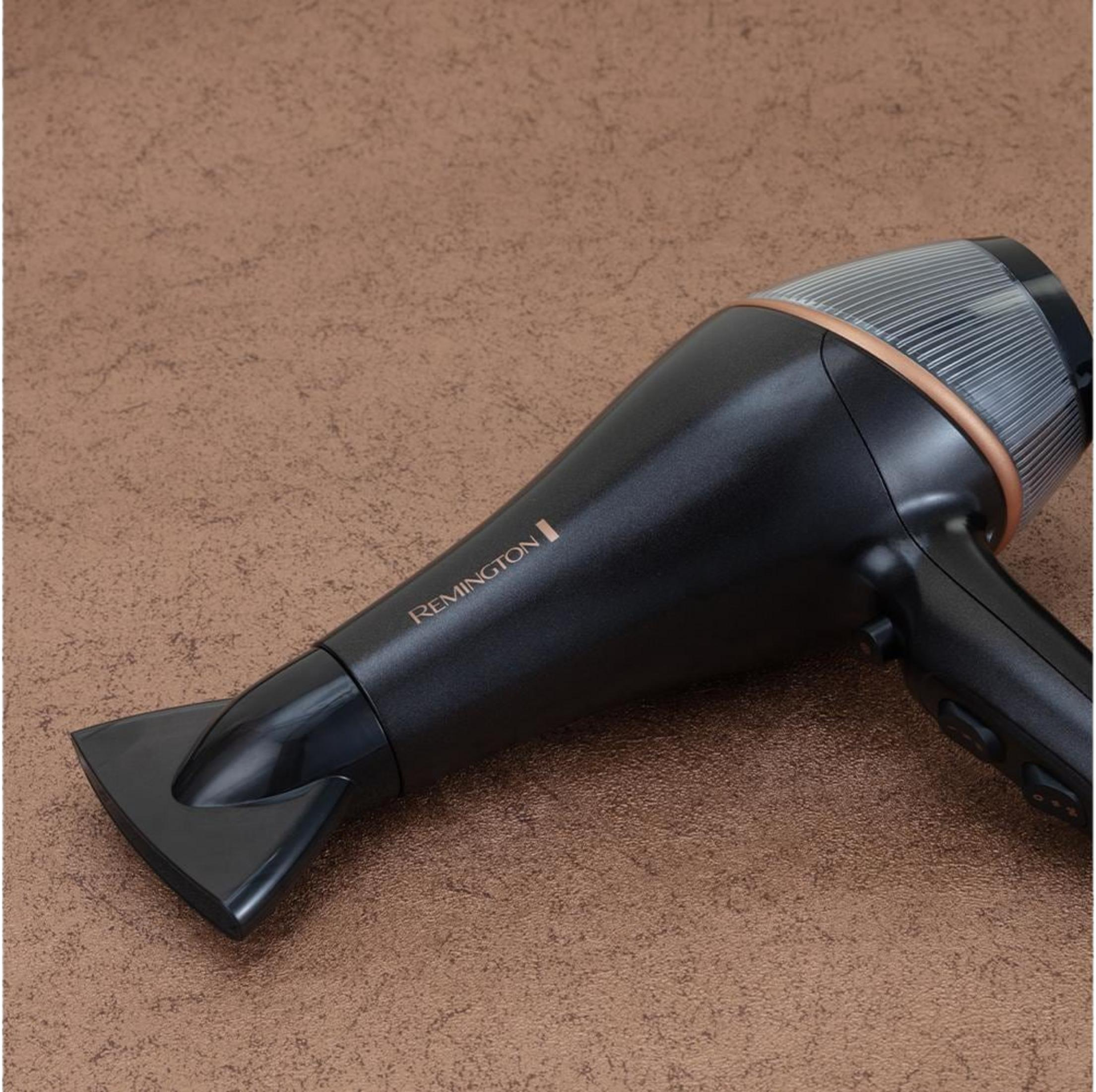 Un asciugacapelli Remington nero con accenti color rame su superficie marrone.