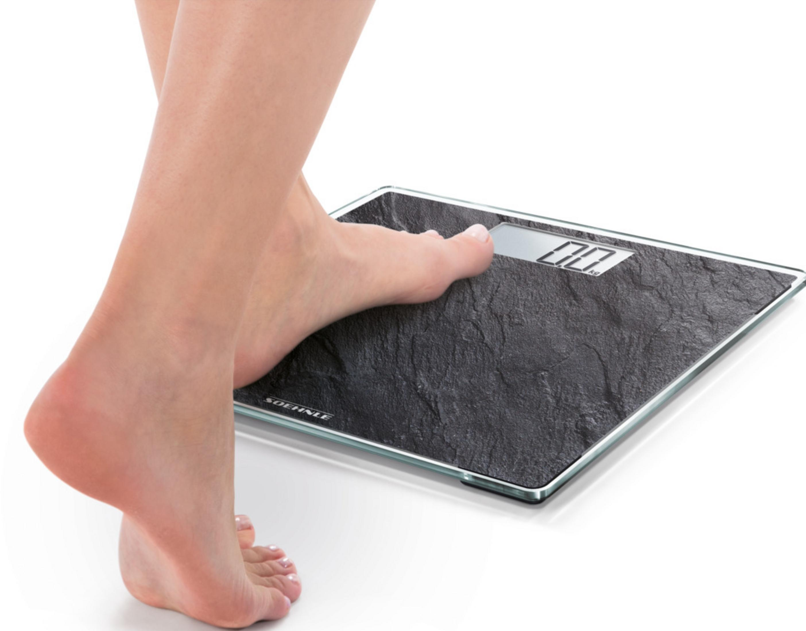 Stopa na ciemnej wadze pokazującej 0,0 kg.