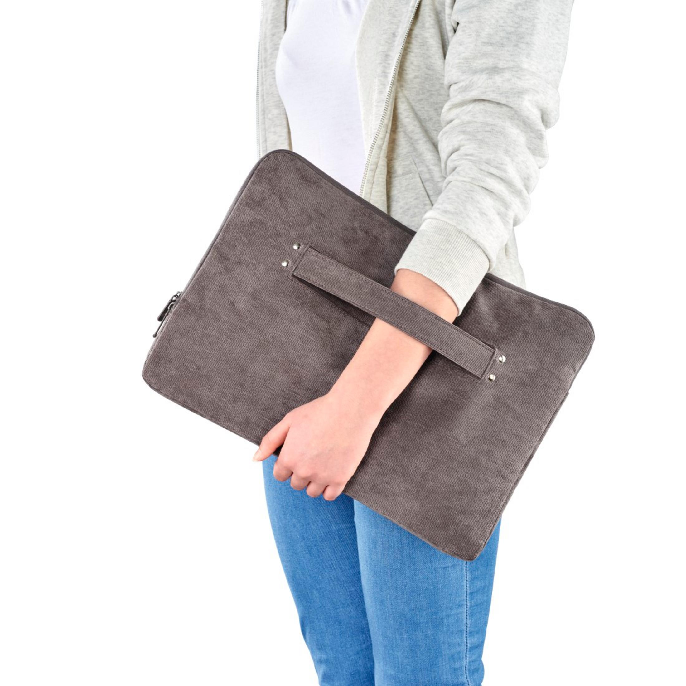 Person in Jeans und Hoodie hält eine graue Laptoptasche.