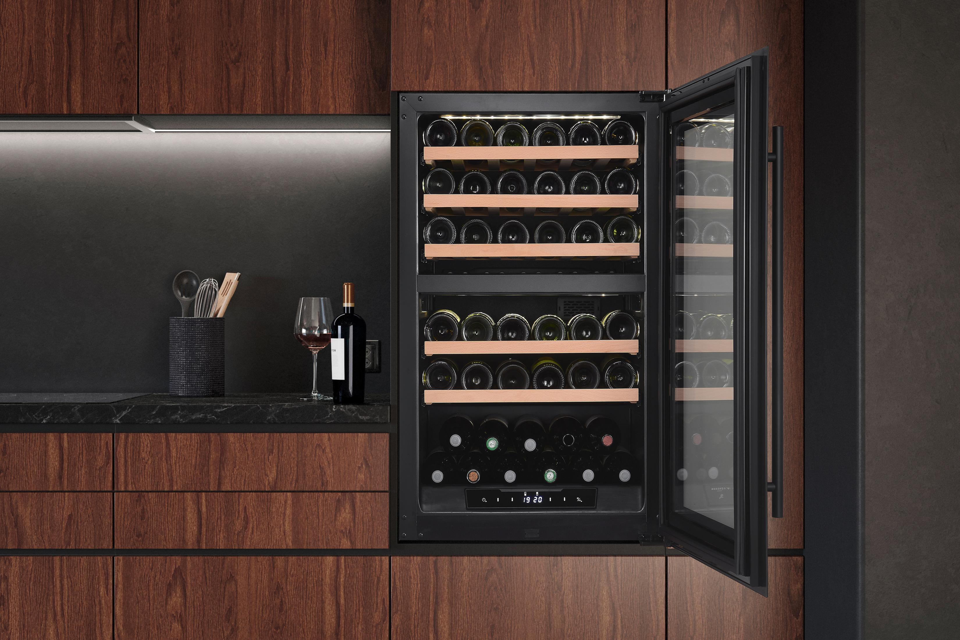 Une cave à vin avec étagères en bois et de nombreuses bouteilles, à côté d'un verre et d'une bouteille.