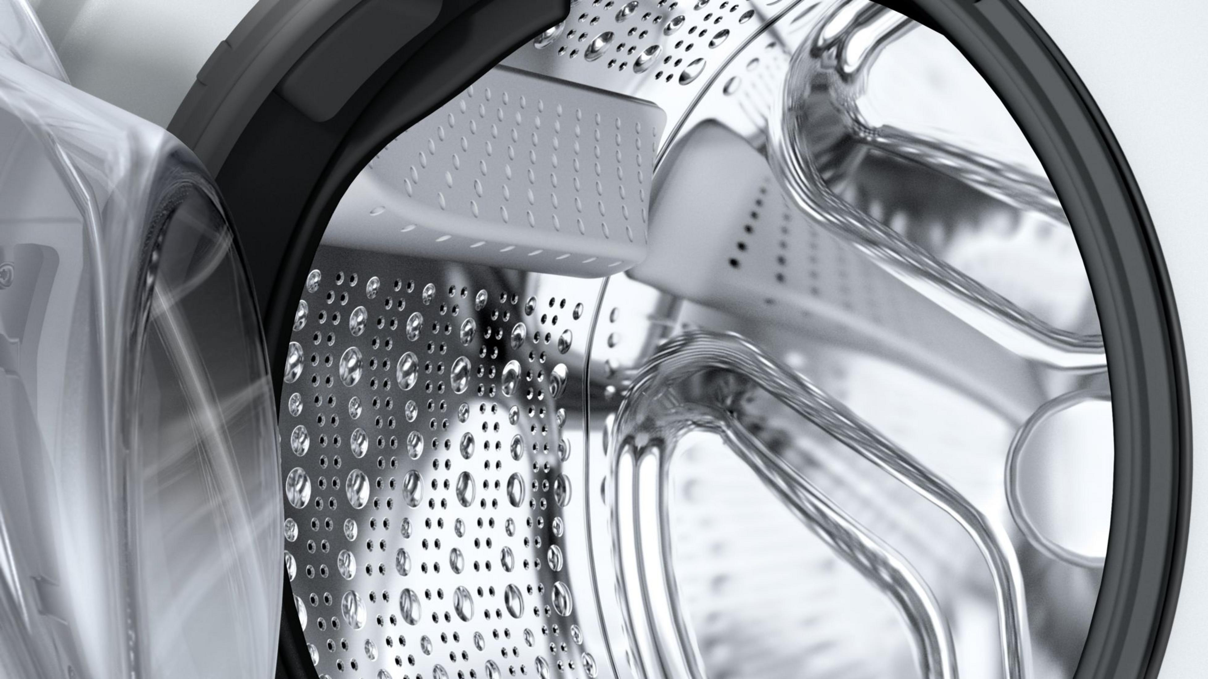 Primo piano del cestello di una lavatrice con gocce d'acqua.