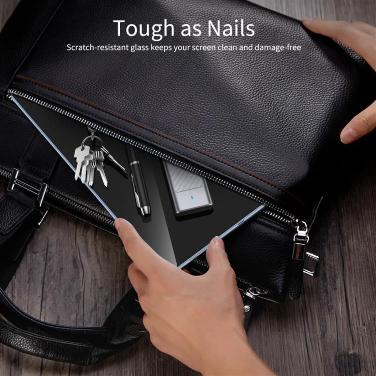 Handen plaatsen een glazen screenprotector in een zwarte leren tas met sleutels.
