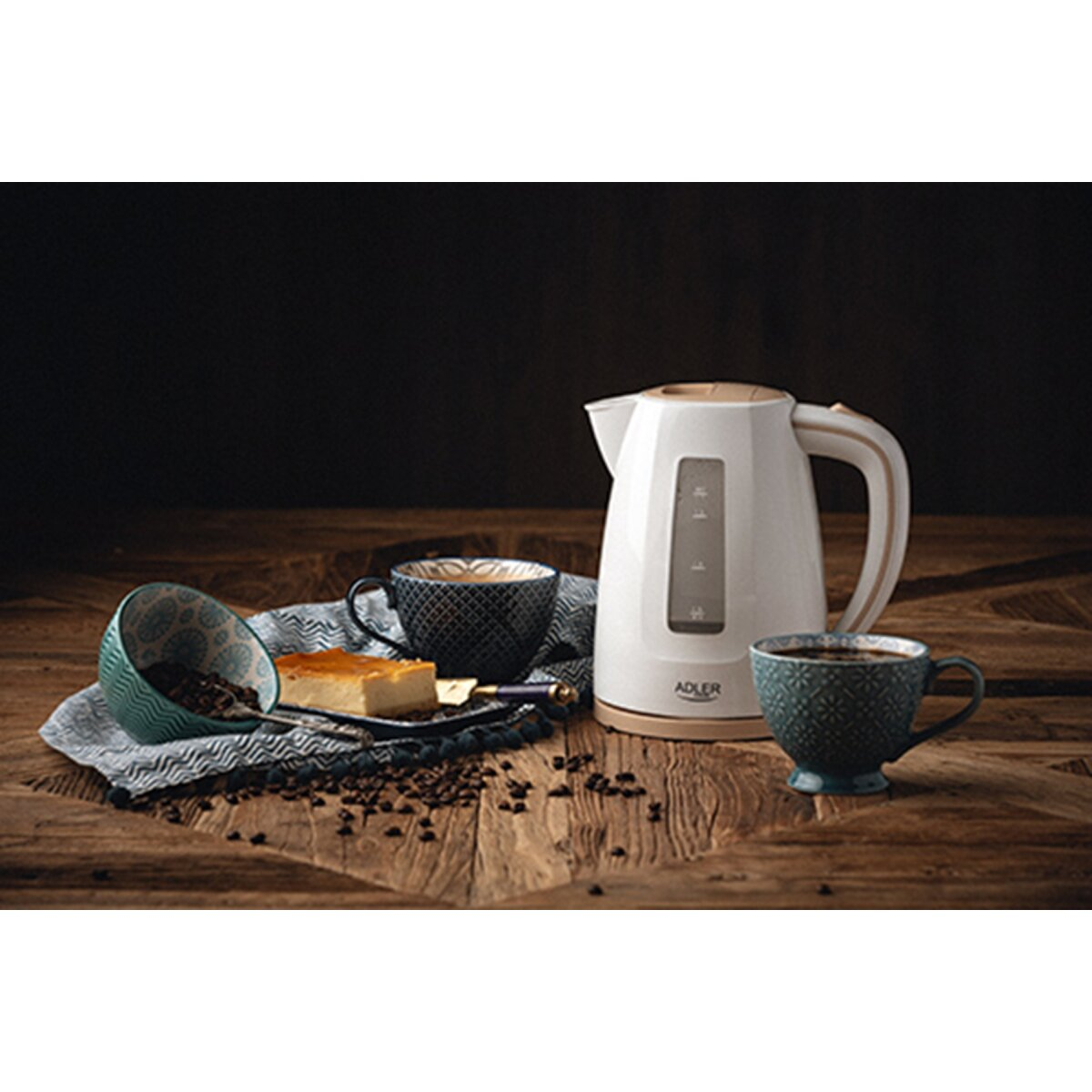 Une bouilloire blanche à côté de tasses à café et d'une part de gâteau.