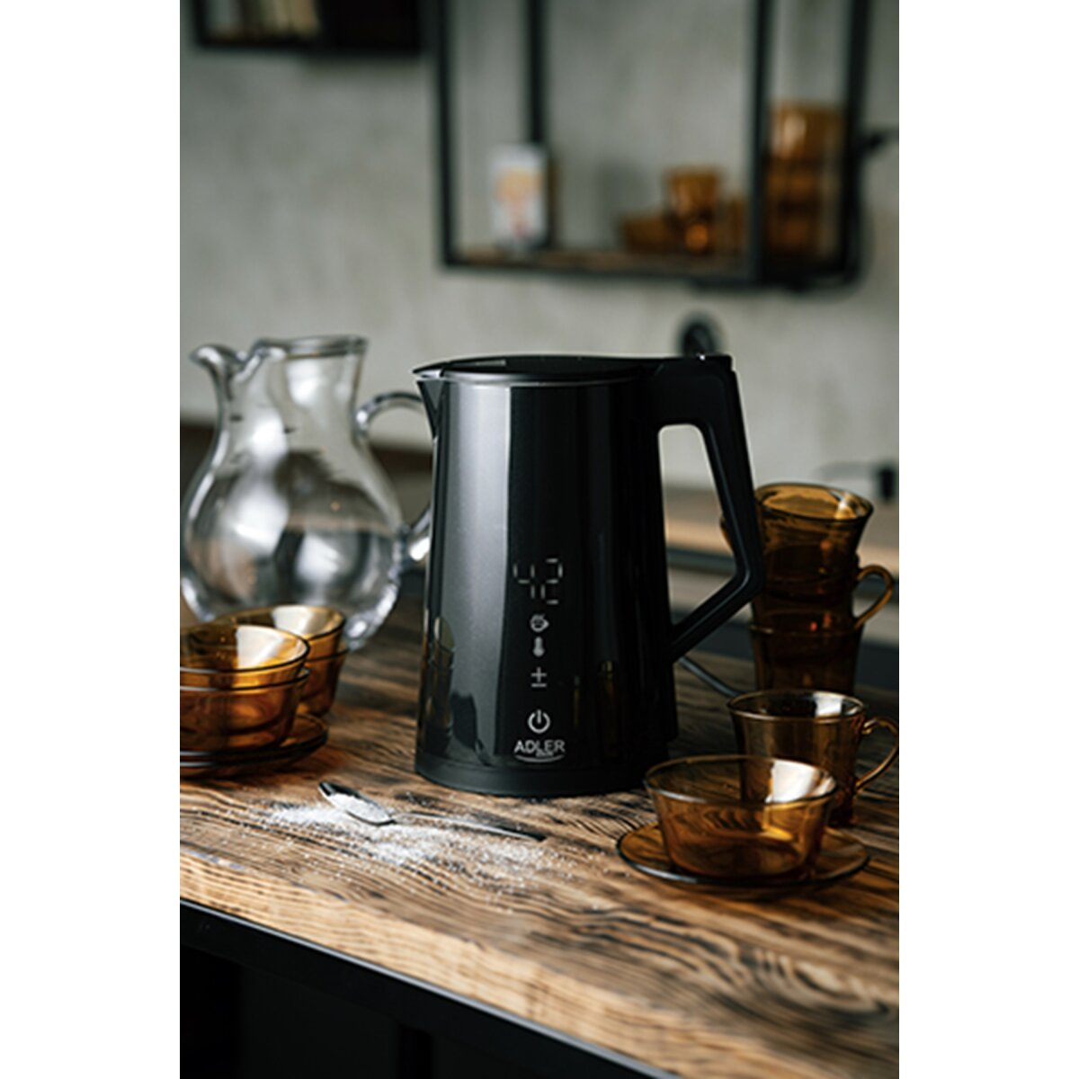 Czajnik elektryczny czarny z dzbankiem szklanym i brązowymi kubkami na drewnie.