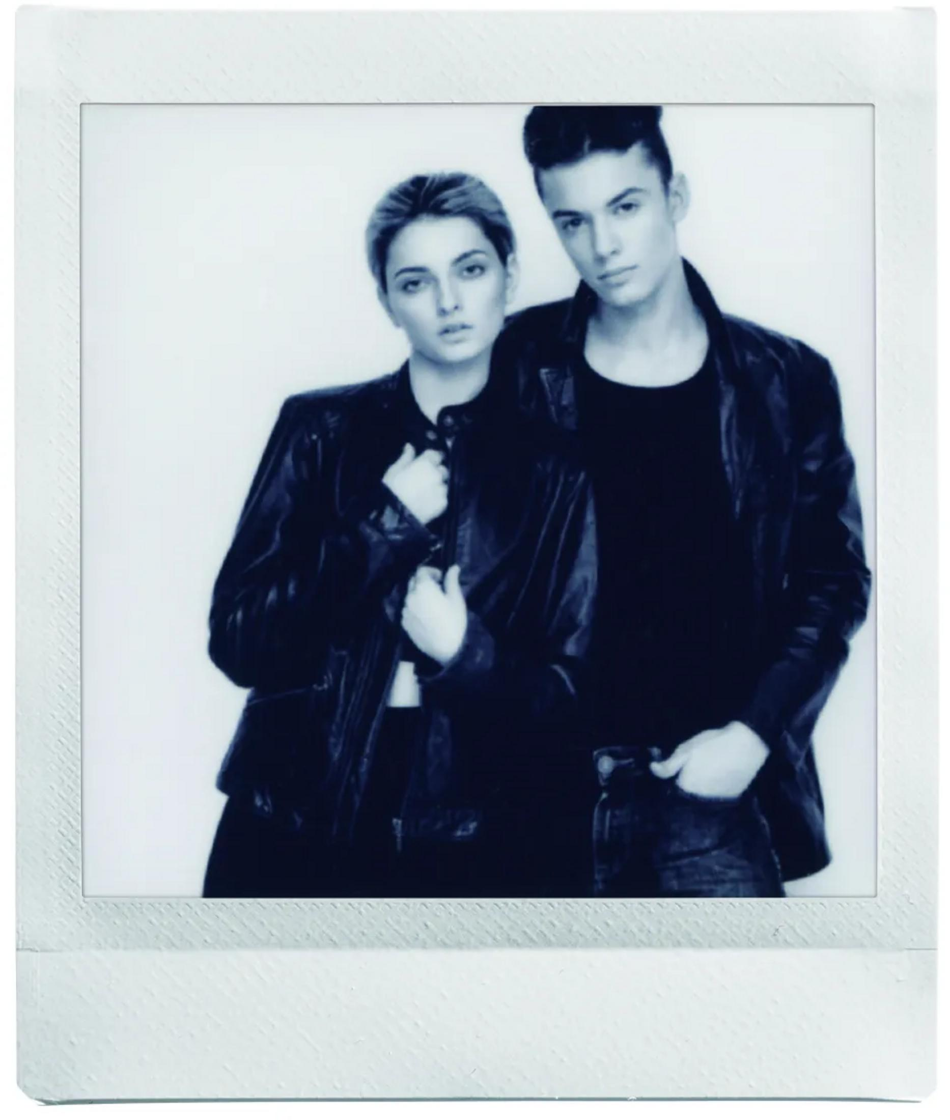 A man and a woman in leather jackets pose against a white background.