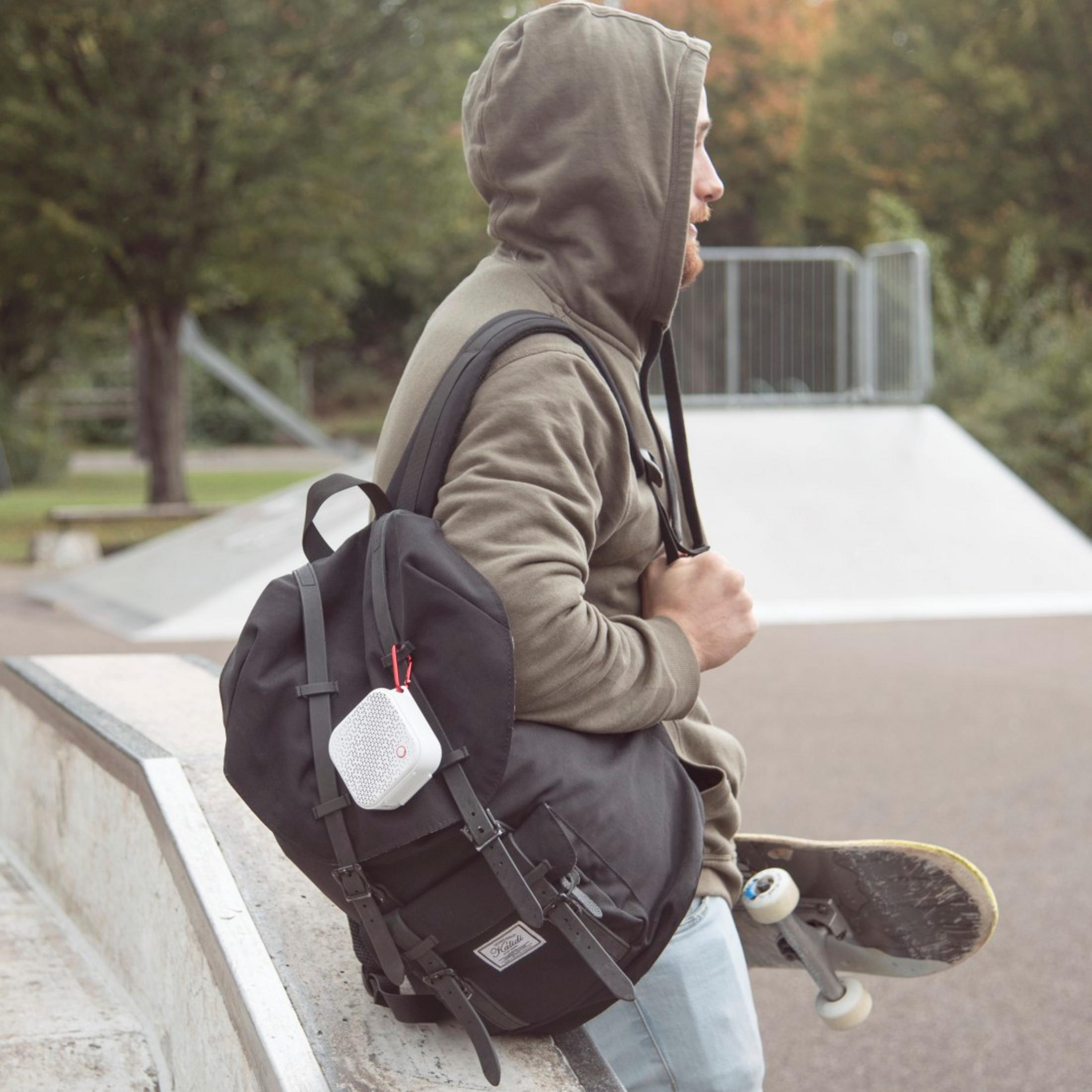 Un uomo con zaino e skateboard in uno skatepark.