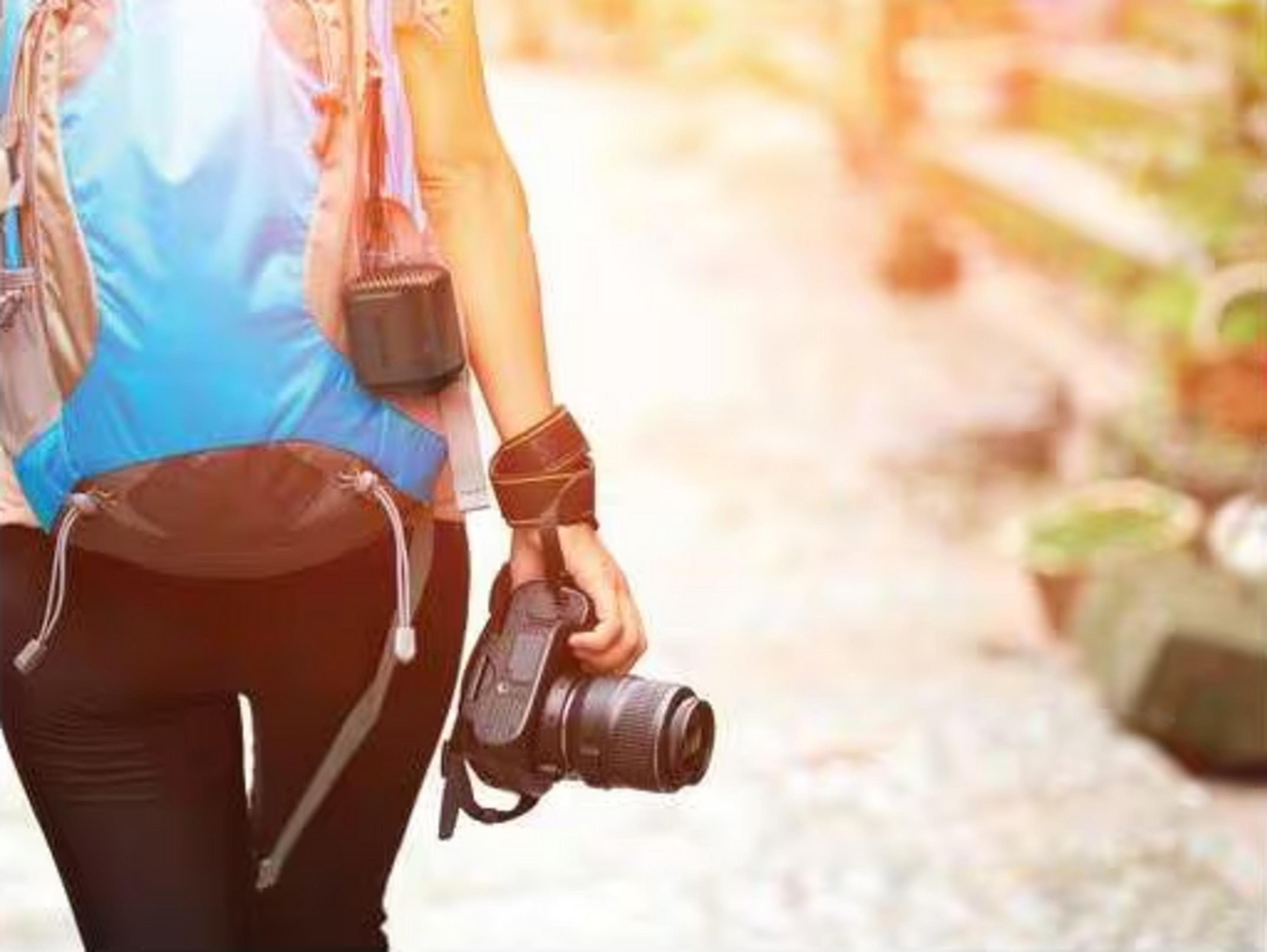 Osoba z plecakiem i aparatem idzie ścieżką.