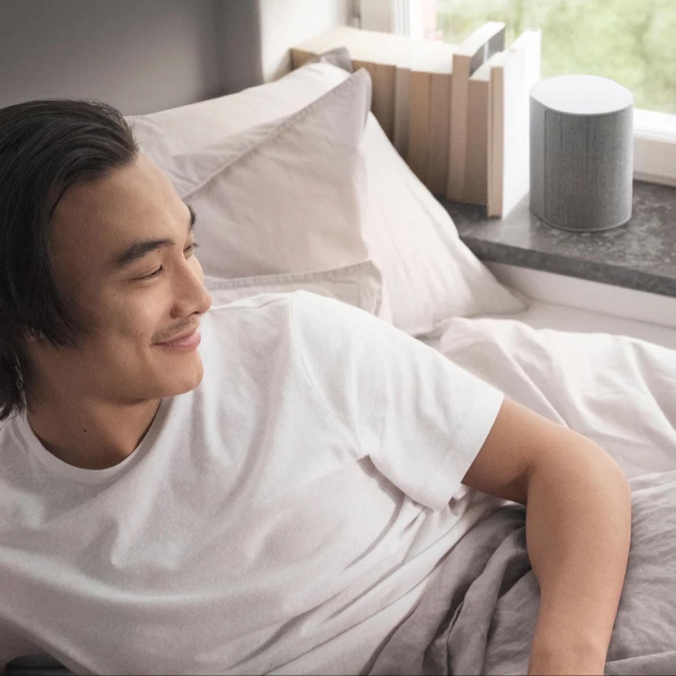 Ein Mann liegt im Bett neben einem Lautsprecher.