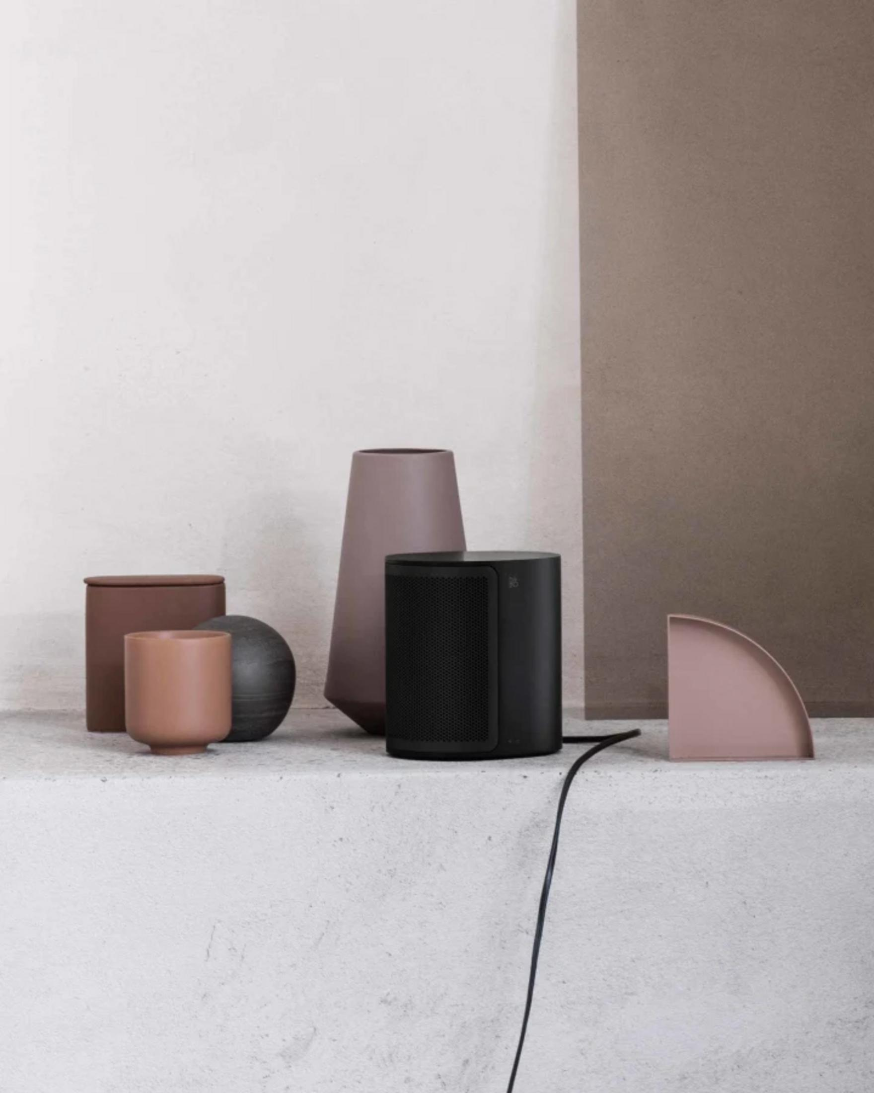 Objetos en superficie de hormigón: jarrón, altavoz, cuenco, contenedor.