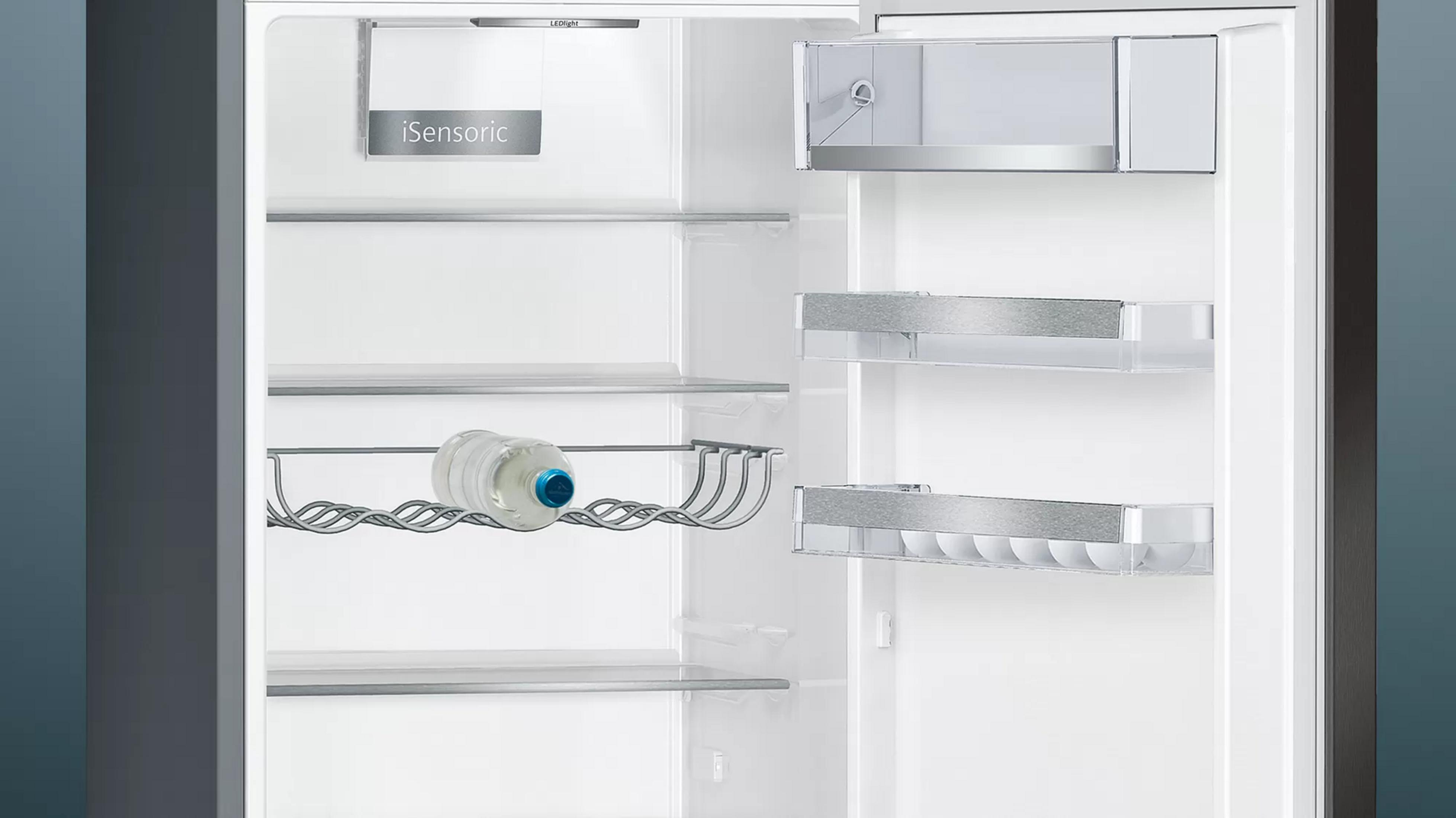 Ein leerer Kühlschrank mit Glasablagen und einer Flasche Wasser.