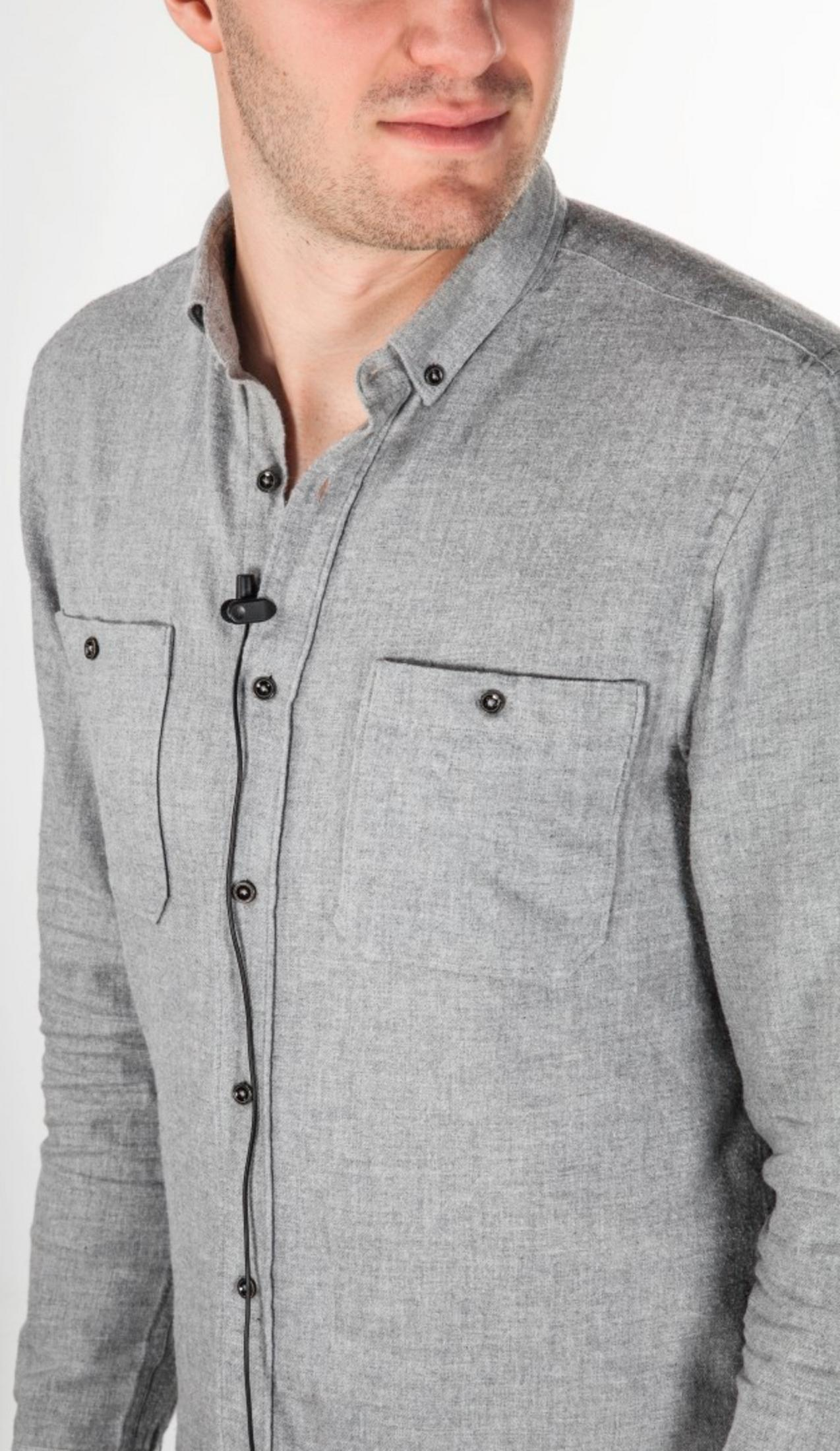 Uomo in camicia grigia con due tasche sul petto e un cavo nero.