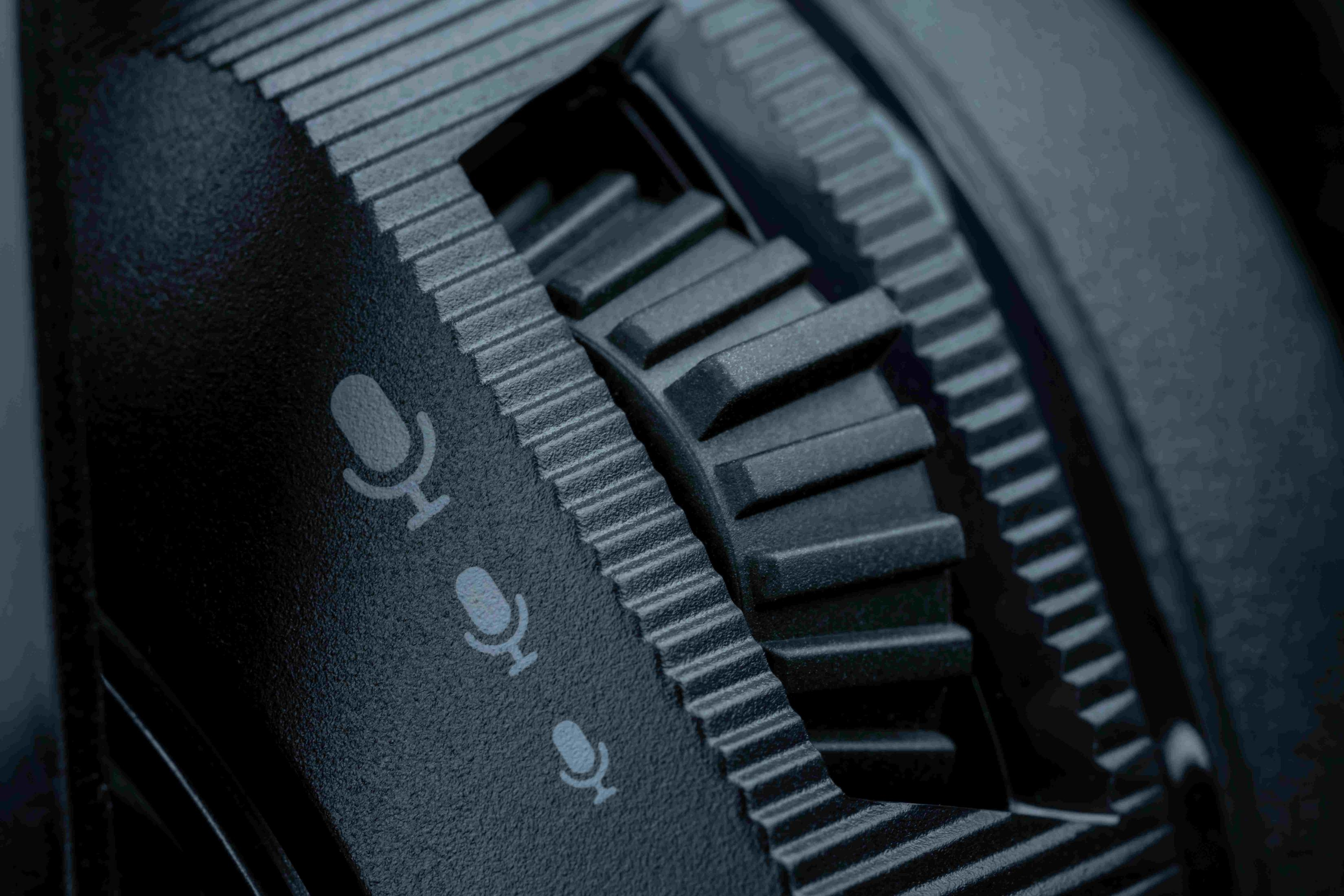 Zbliżenie czarnego pokrętła z ikonami mikrofonu i radełkowaniem.