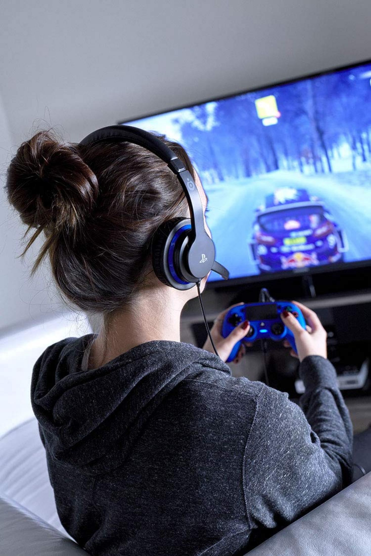 Eine Person mit Kopfhörern spielt ein Autorennen auf einem Fernseher.