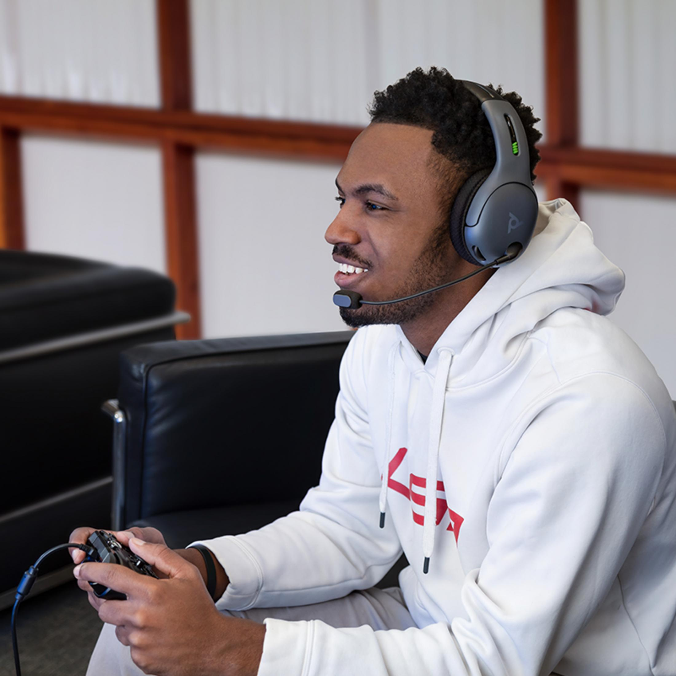 Mężczyzna w słuchawkach z mikrofonem gra w gry wideo za pomocą kontrolera.