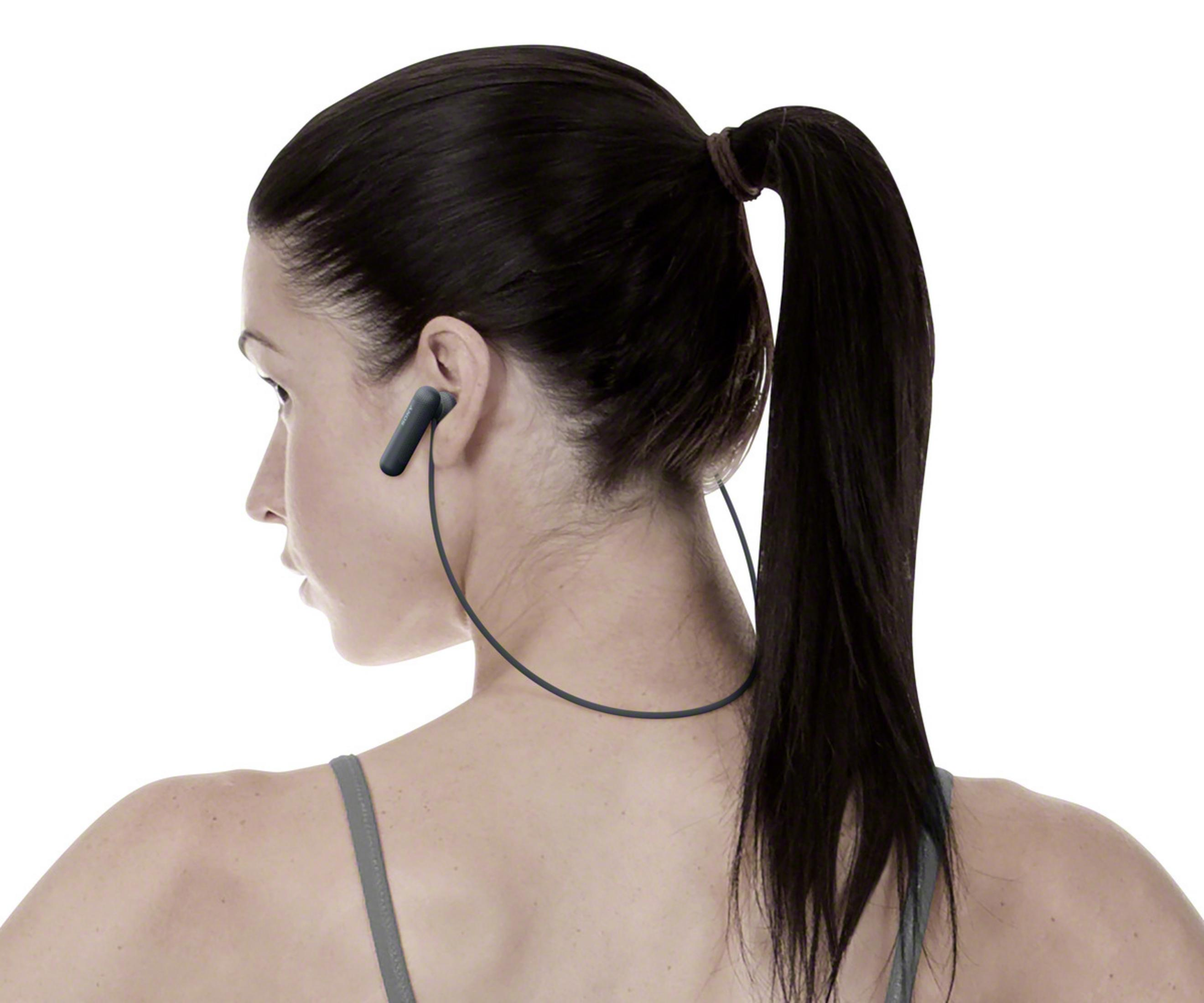 Kobieta z ciemnymi włosami w kucyku nosi czarny słuchawki.