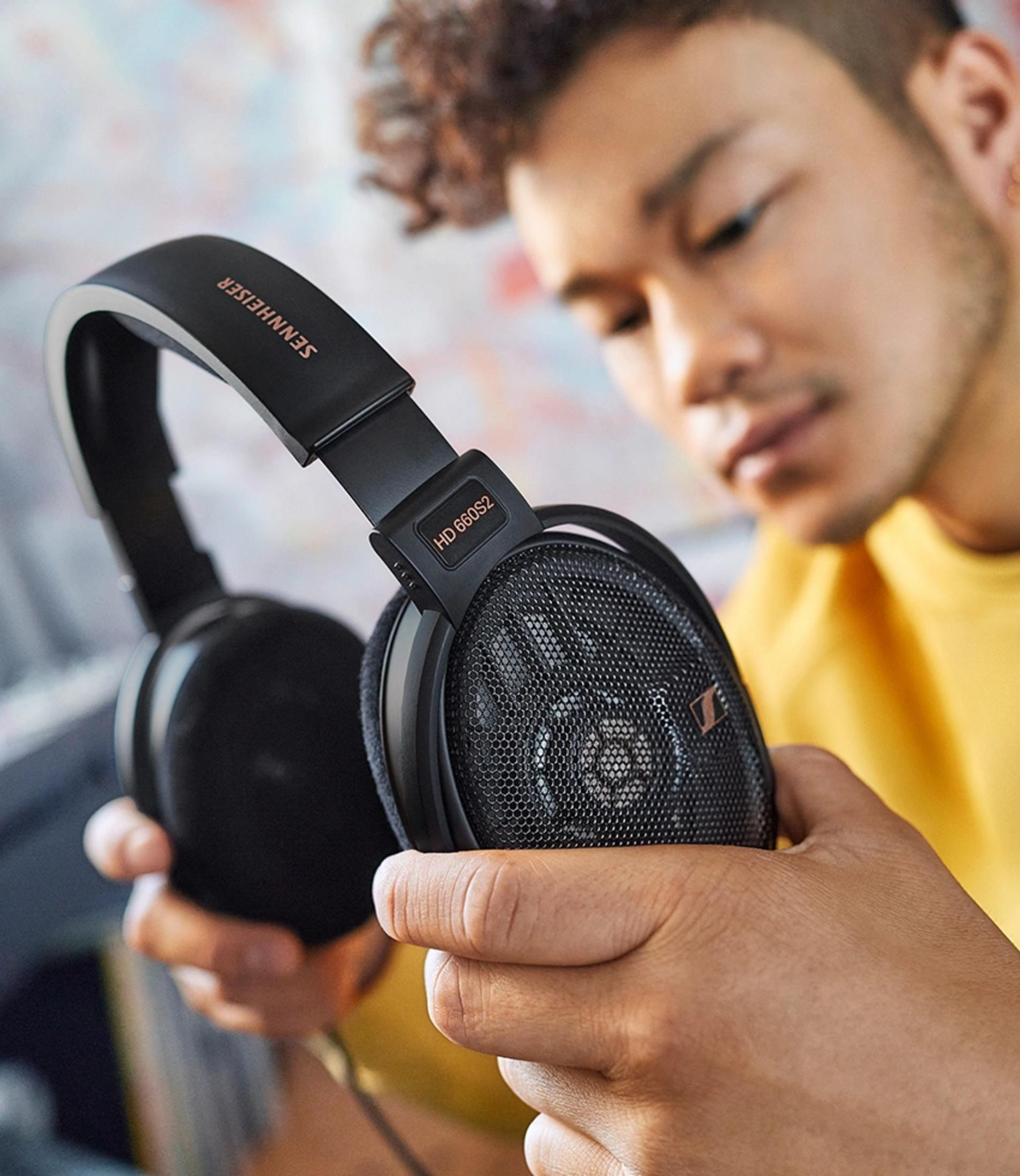 Mann hält schwarze Sennheiser HD 660S2 Kopfhörer mit Netzoberfläche.