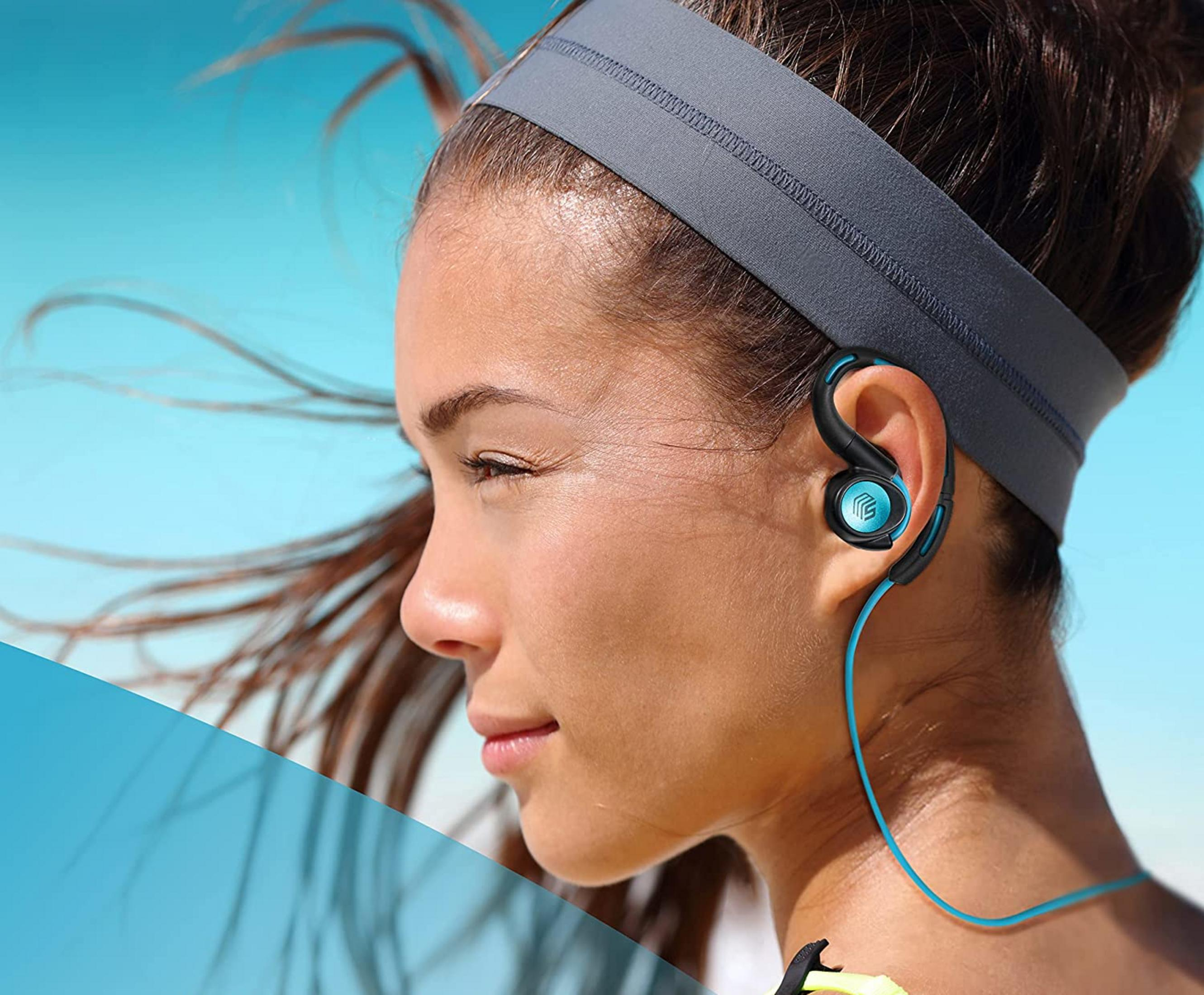 Kobieta w niebiesko-czarnych słuchawkach i opasce, niebieskie niebo w tle.