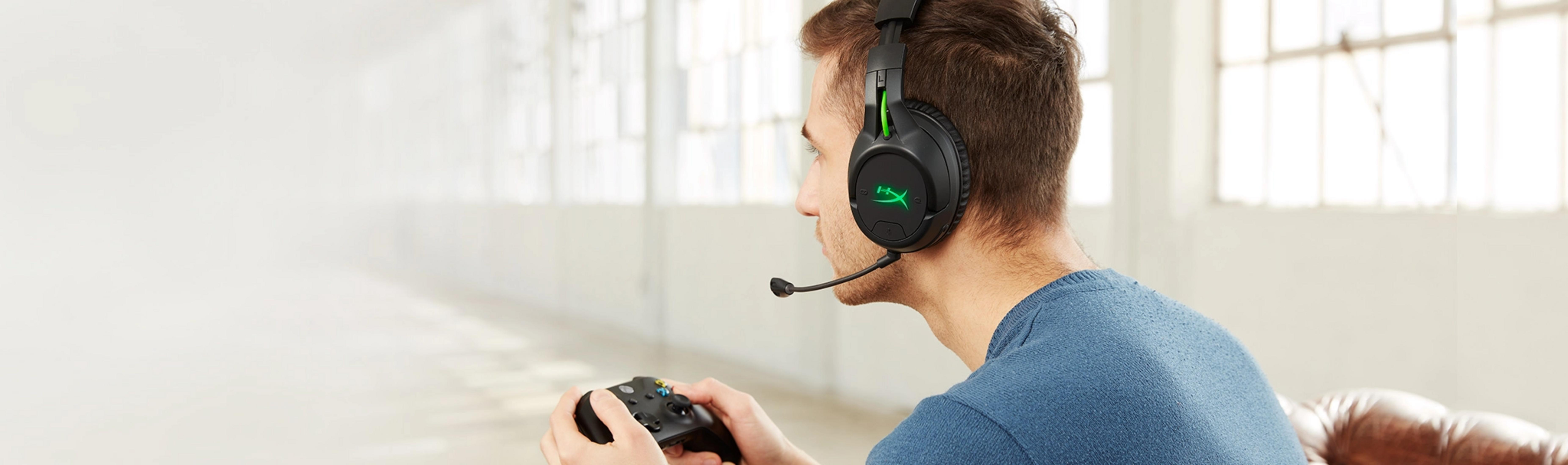 Ein Mann mit Kopfhörern und Mikrofon hält einen Controller.