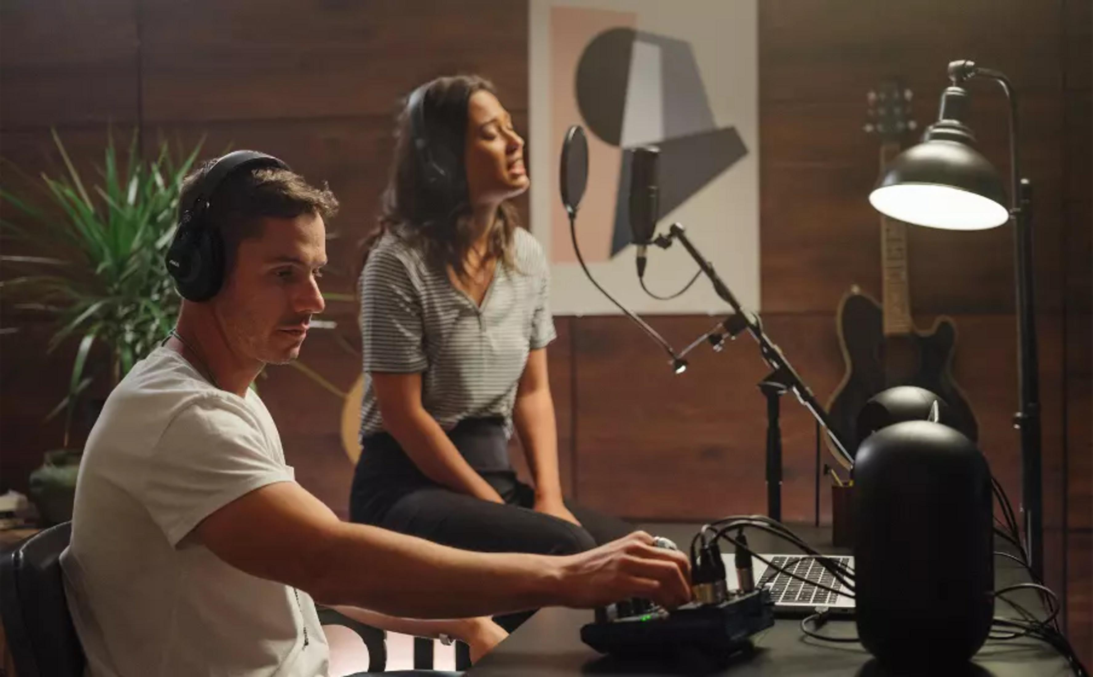Un hombre con auriculares y una mujer cantando a un micrófono.
