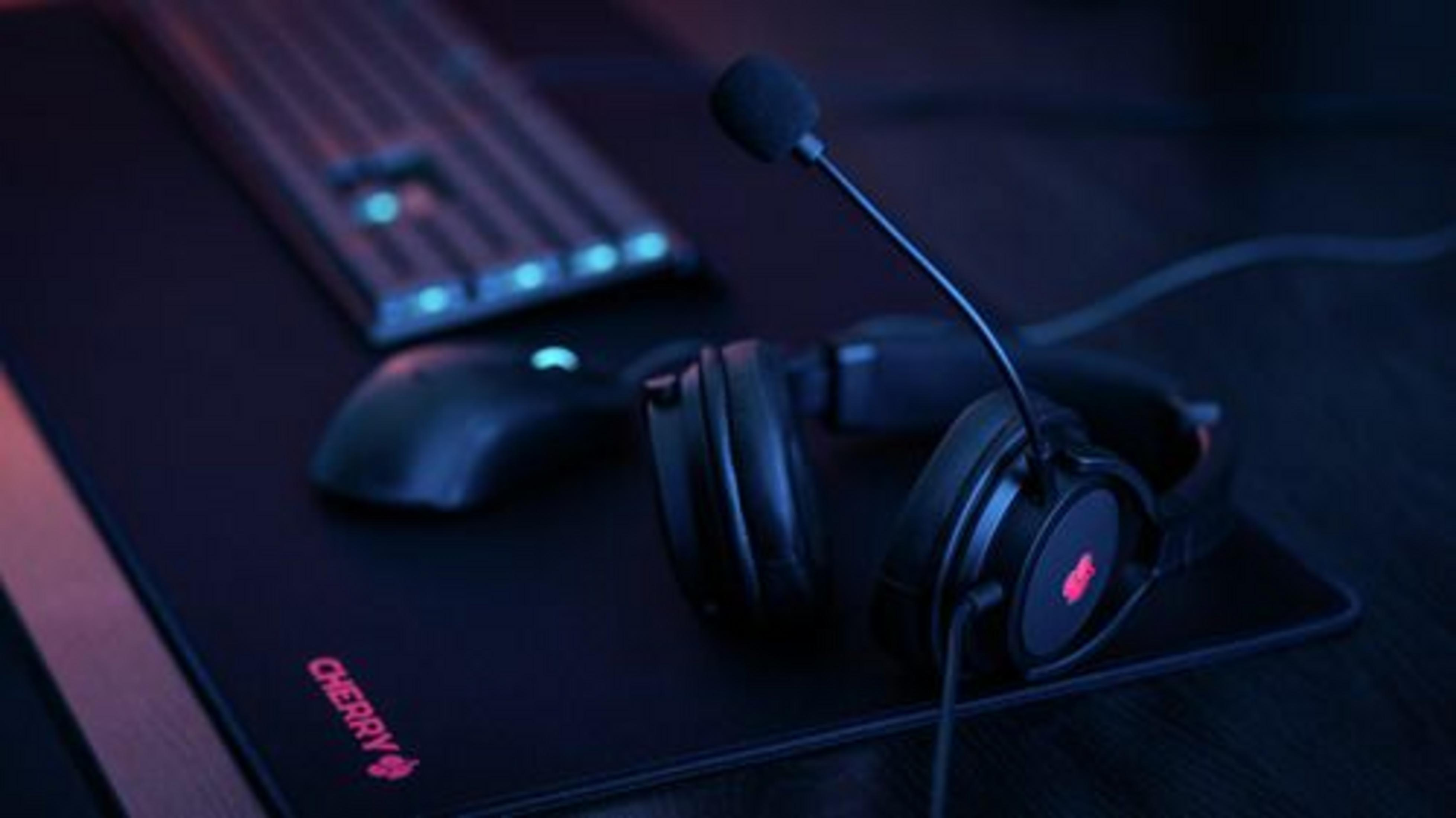 Ein Gaming-Headset, eine Maus und eine Tastatur auf einer schwarzen Matte.