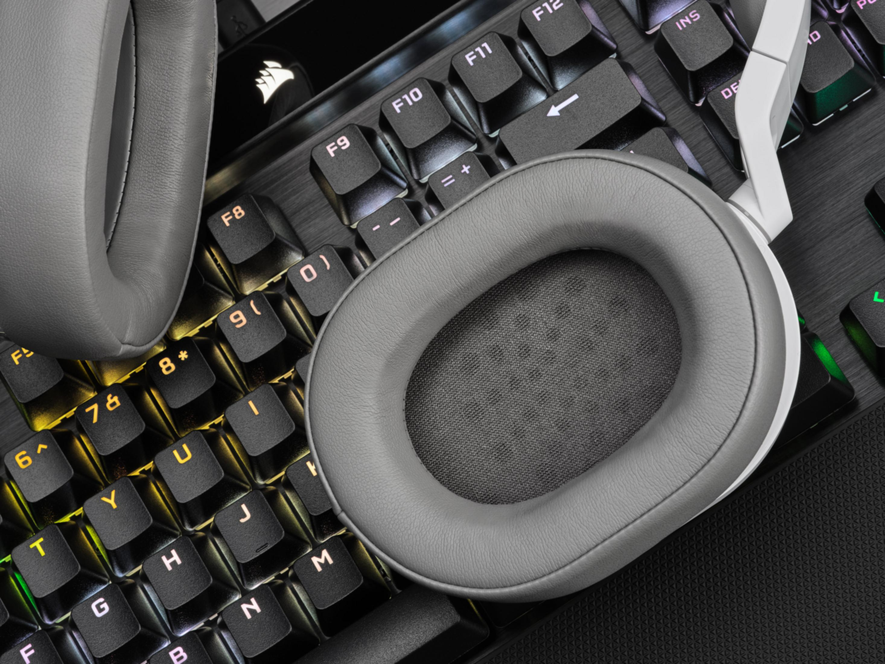Gray headphones rest on a backlit keyboard.