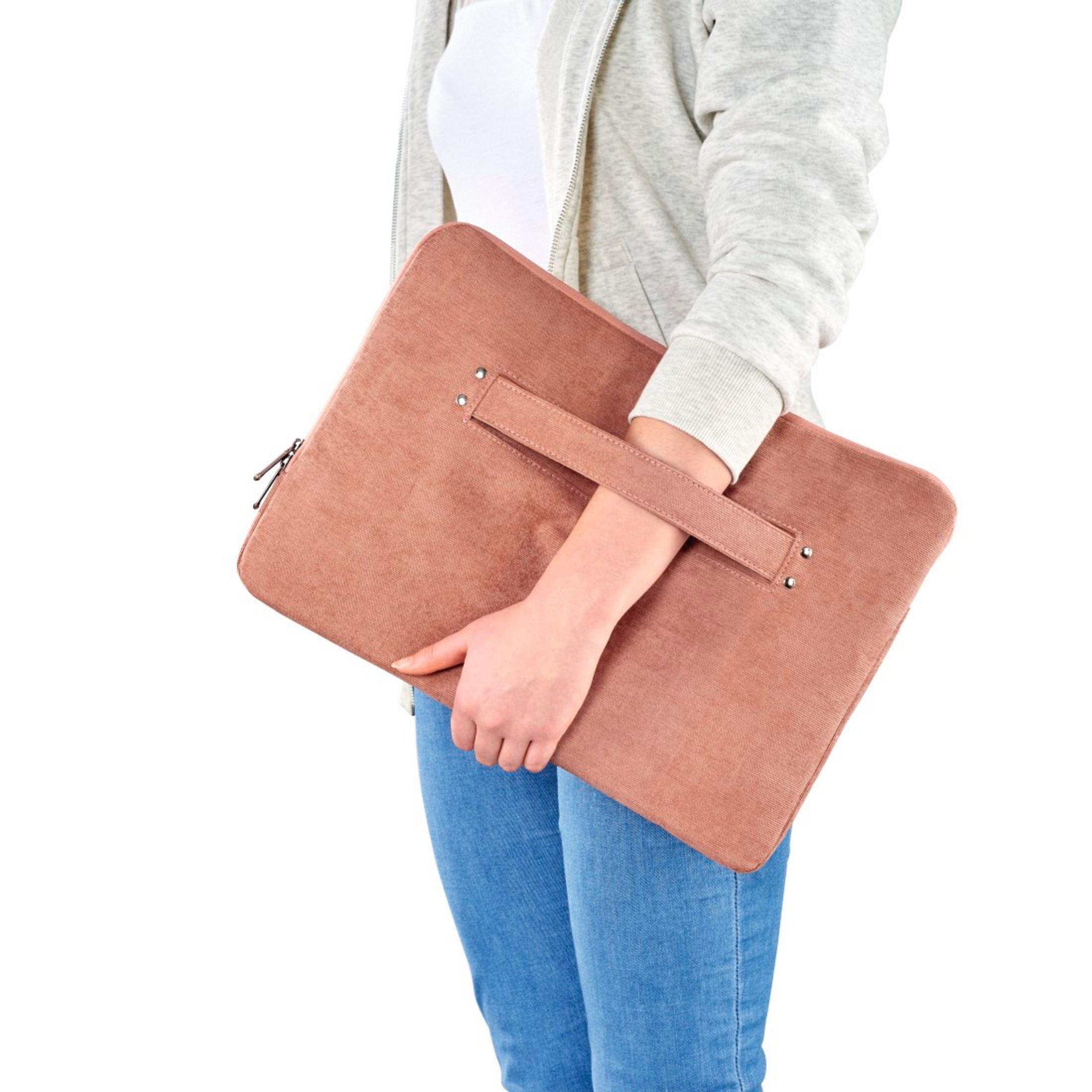 Osoba w dżinsach i szarej bluzie z kapturem trzyma różową torbę na laptopa.