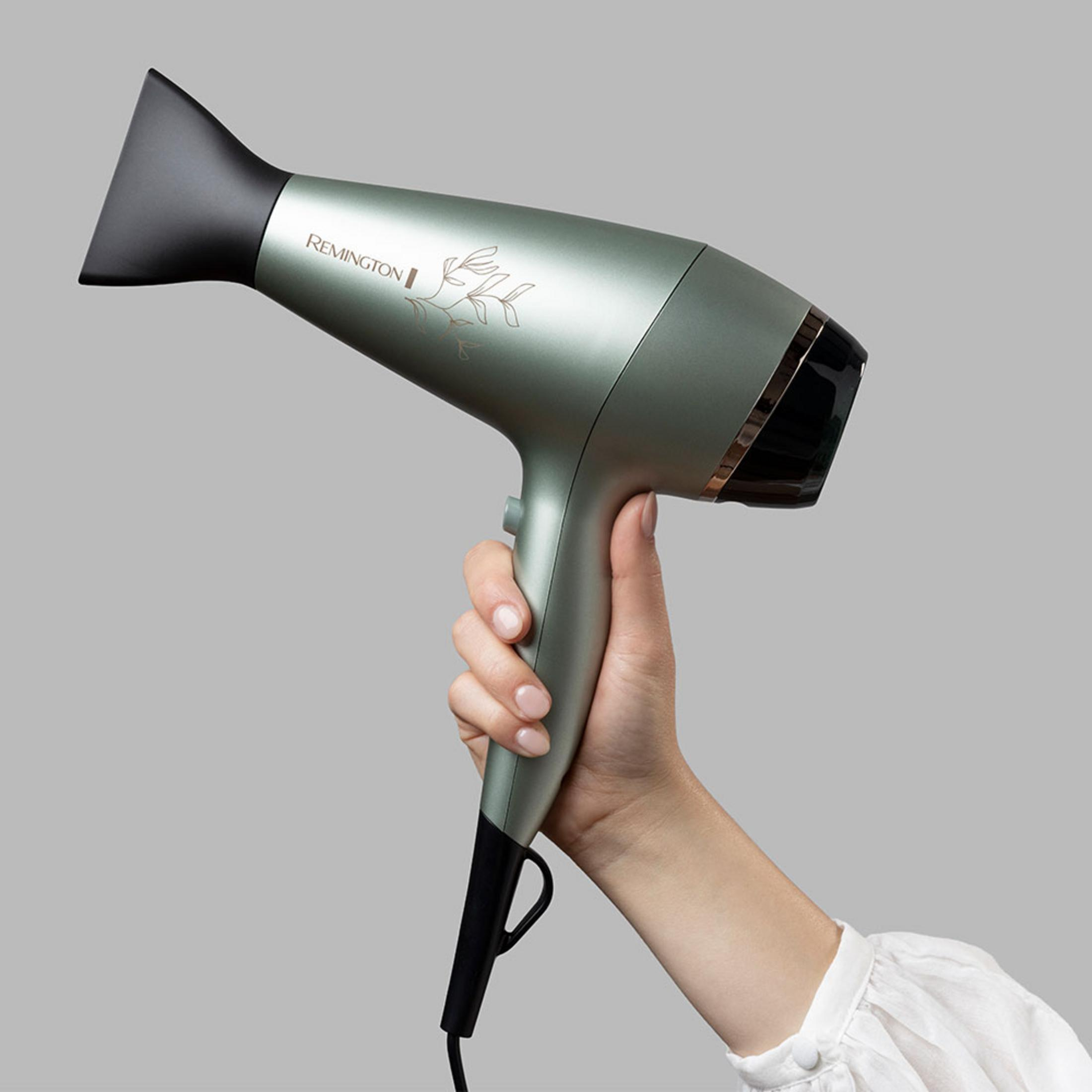 Eine Hand hält einen mintgrünen Remington-Haartrockner mit schwarzer Düse.