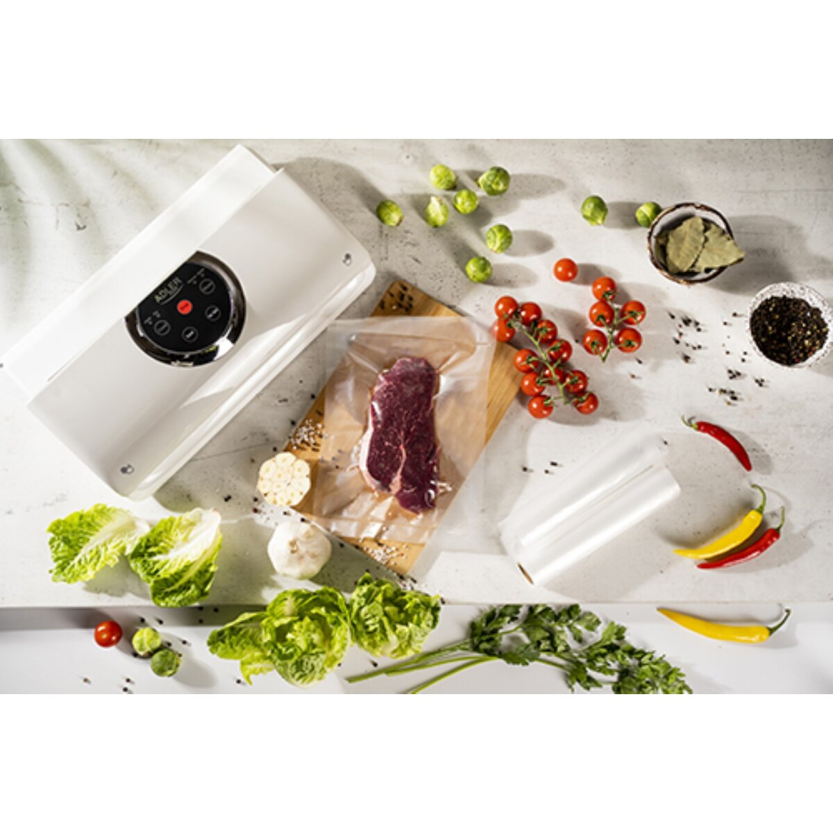 Zgrzewarka próżniowa z mięsem, warzywami i przyprawami na blacie.