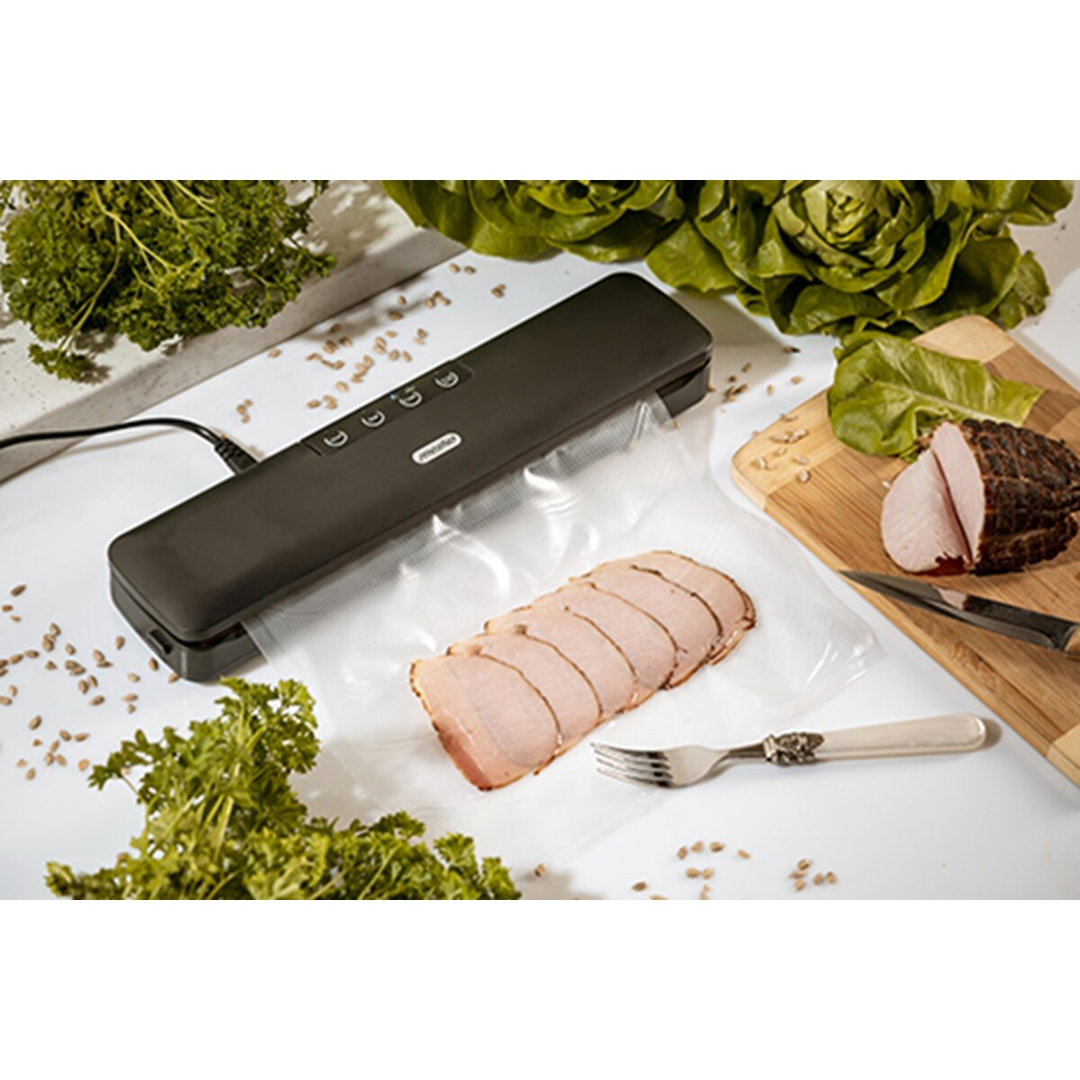 Ein Vakuumierer versiegelt geschnittenes Fleisch in einer Plastikhülle, daneben Fleisch und Salat.