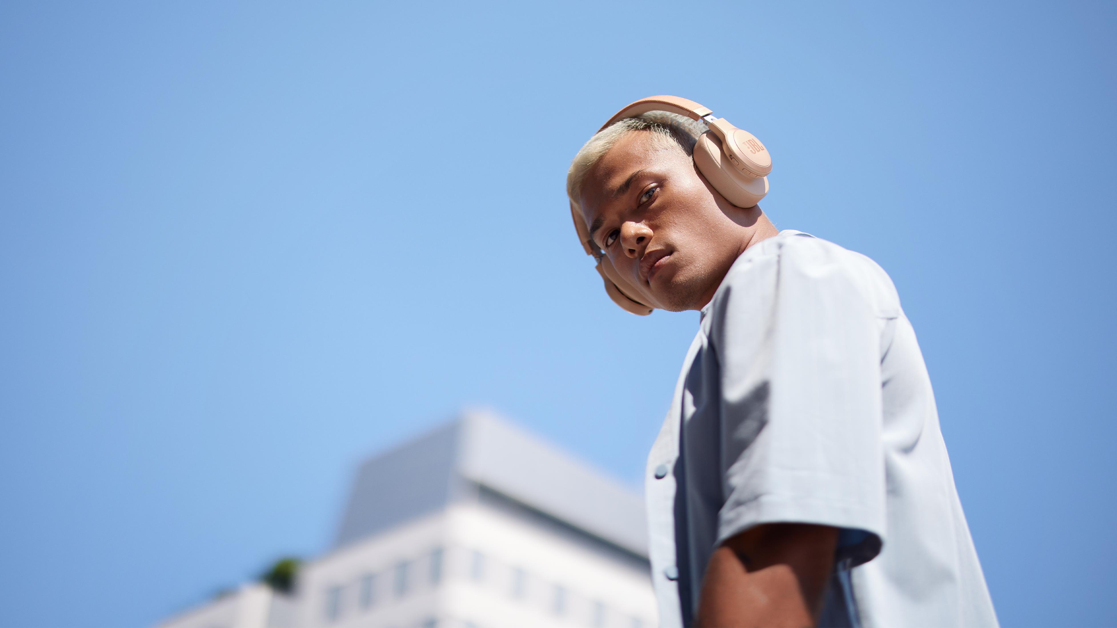 Mężczyzna z blond włosami i słuchawkami patrzy w dół.