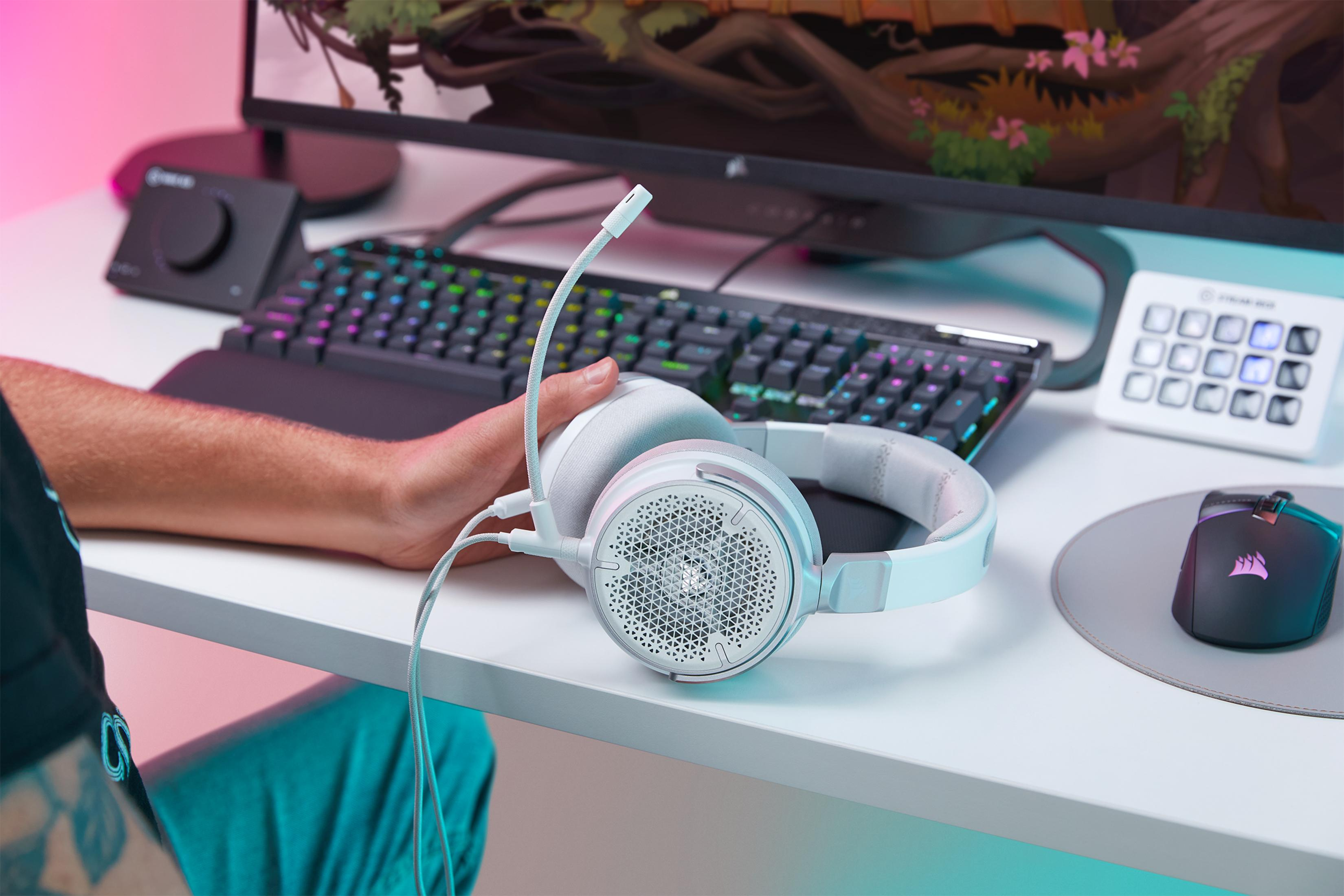 Białe słuchawki z mikrofonem leżą na biurku obok klawiatury i myszy.