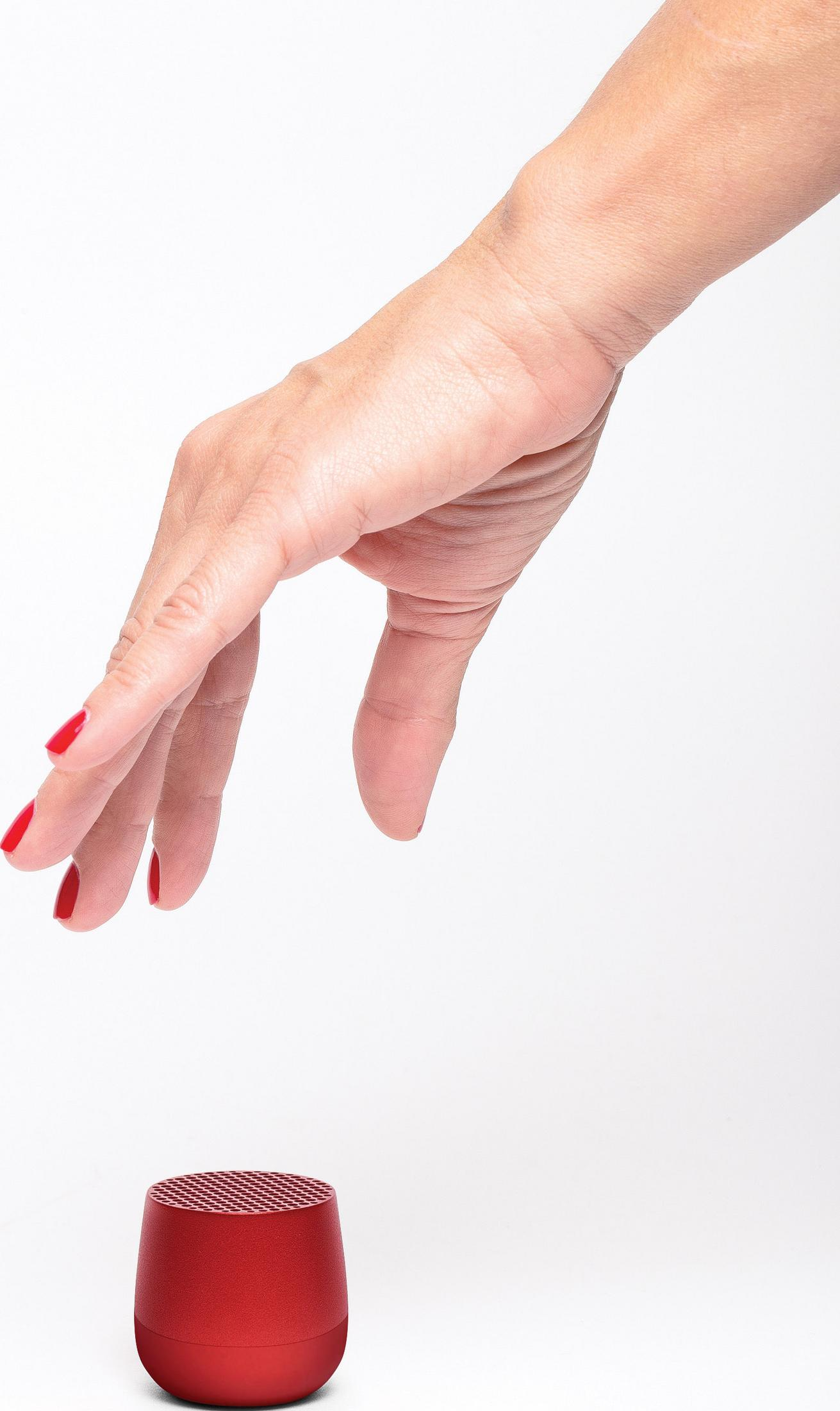Eine Hand mit roten Nägeln nähert sich einem roten Lautsprecher.