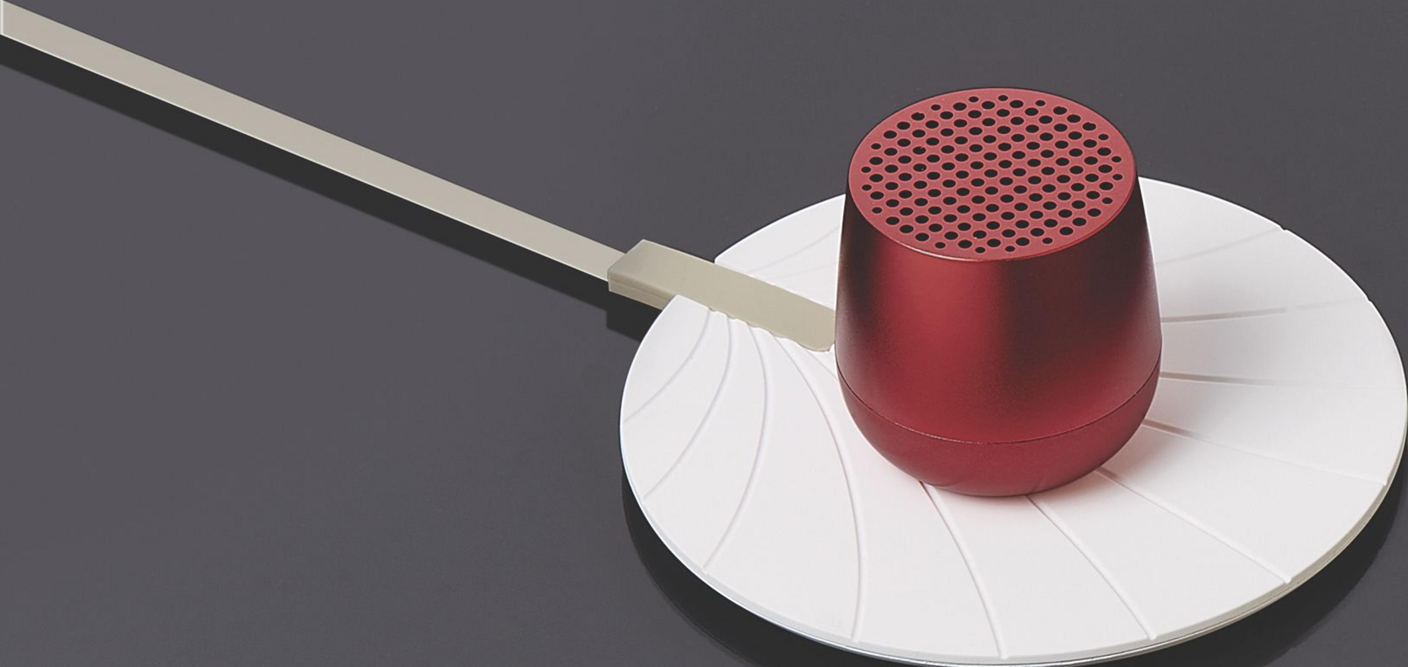 Roter Lautsprecher auf weißer Unterlage mit Kabel auf dunklem Hintergrund.