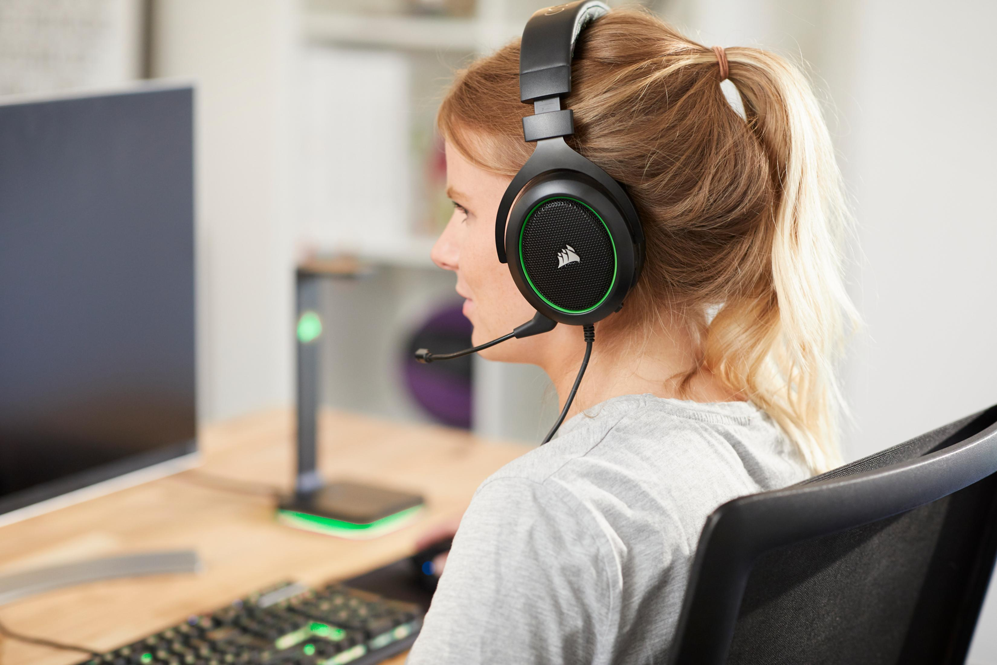 Eine Frau mit Kopfhörern sitzt vor einem Computerbildschirm.