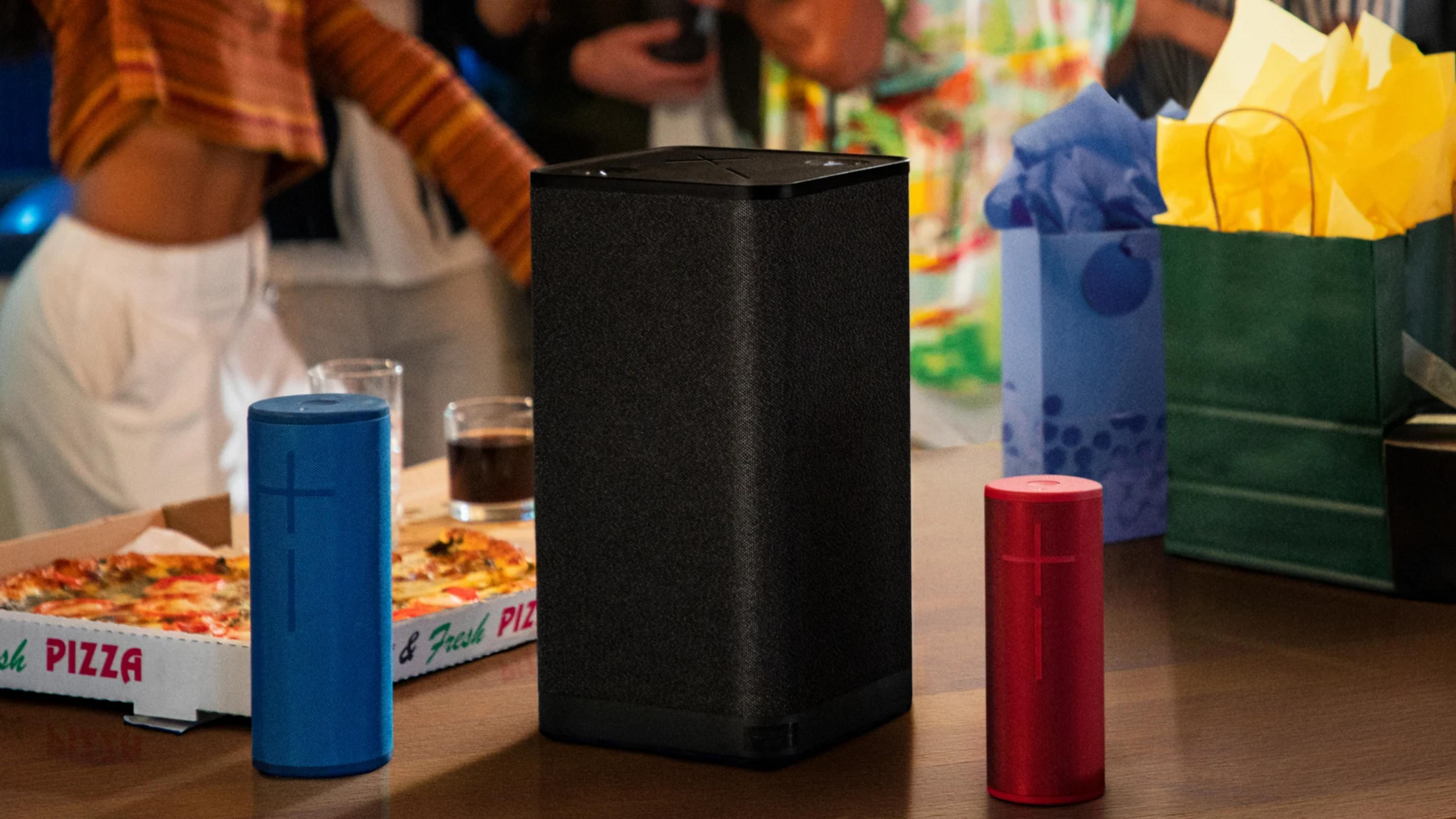 Niebieski, czarny i czerwony głośnik na stole z pizzą.