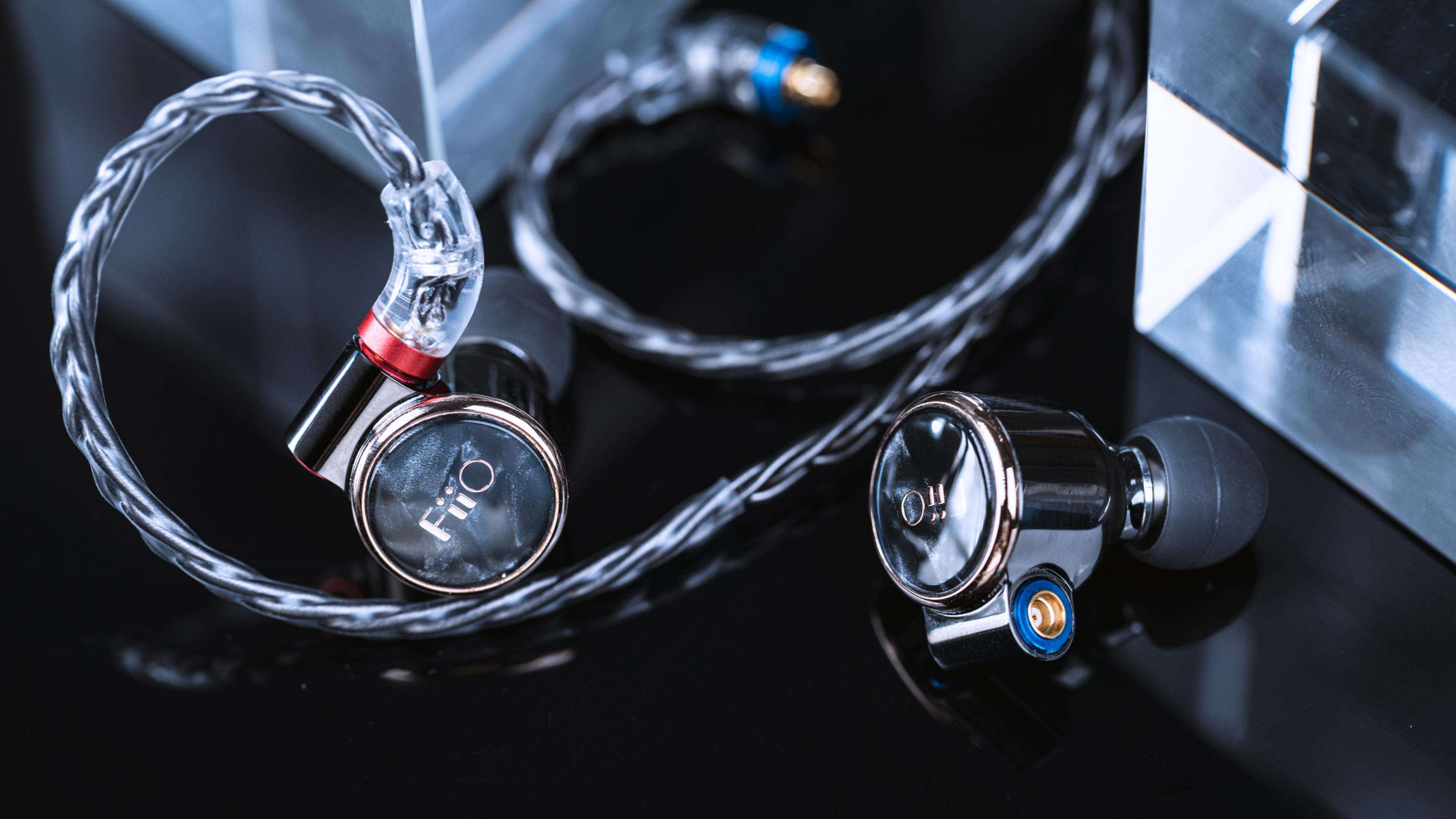 Primer plano de auriculares FiiO con cable plateado y audífonos negros.