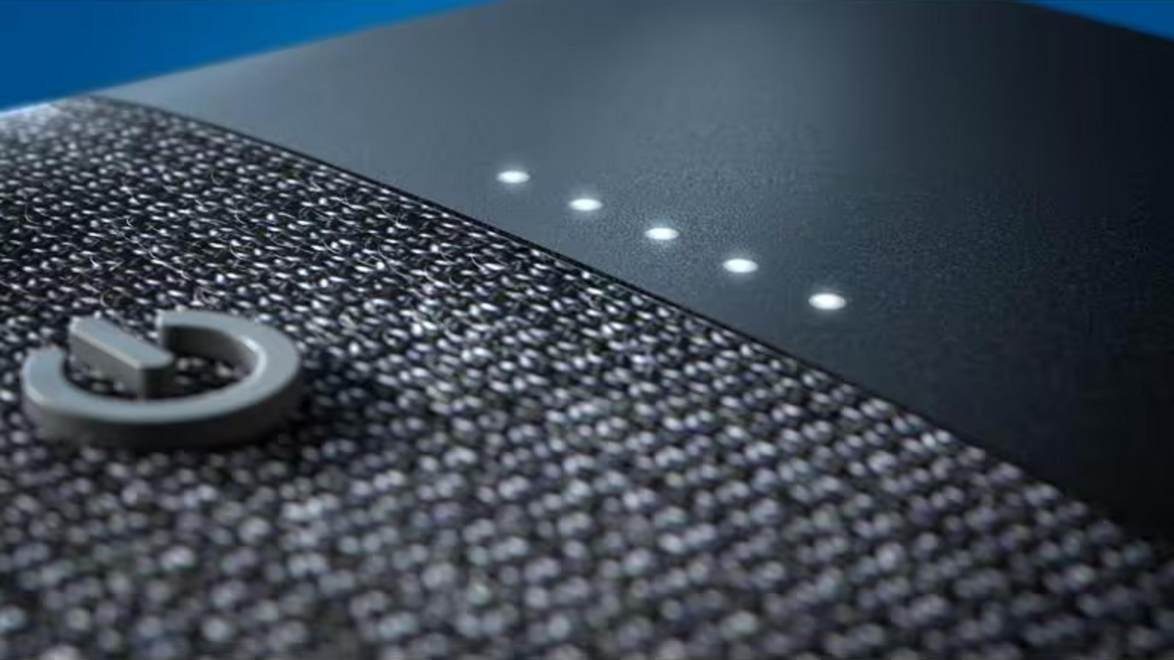 Szary symbol zasilania na teksturowanej powierzchni z podświetlonymi światłami.