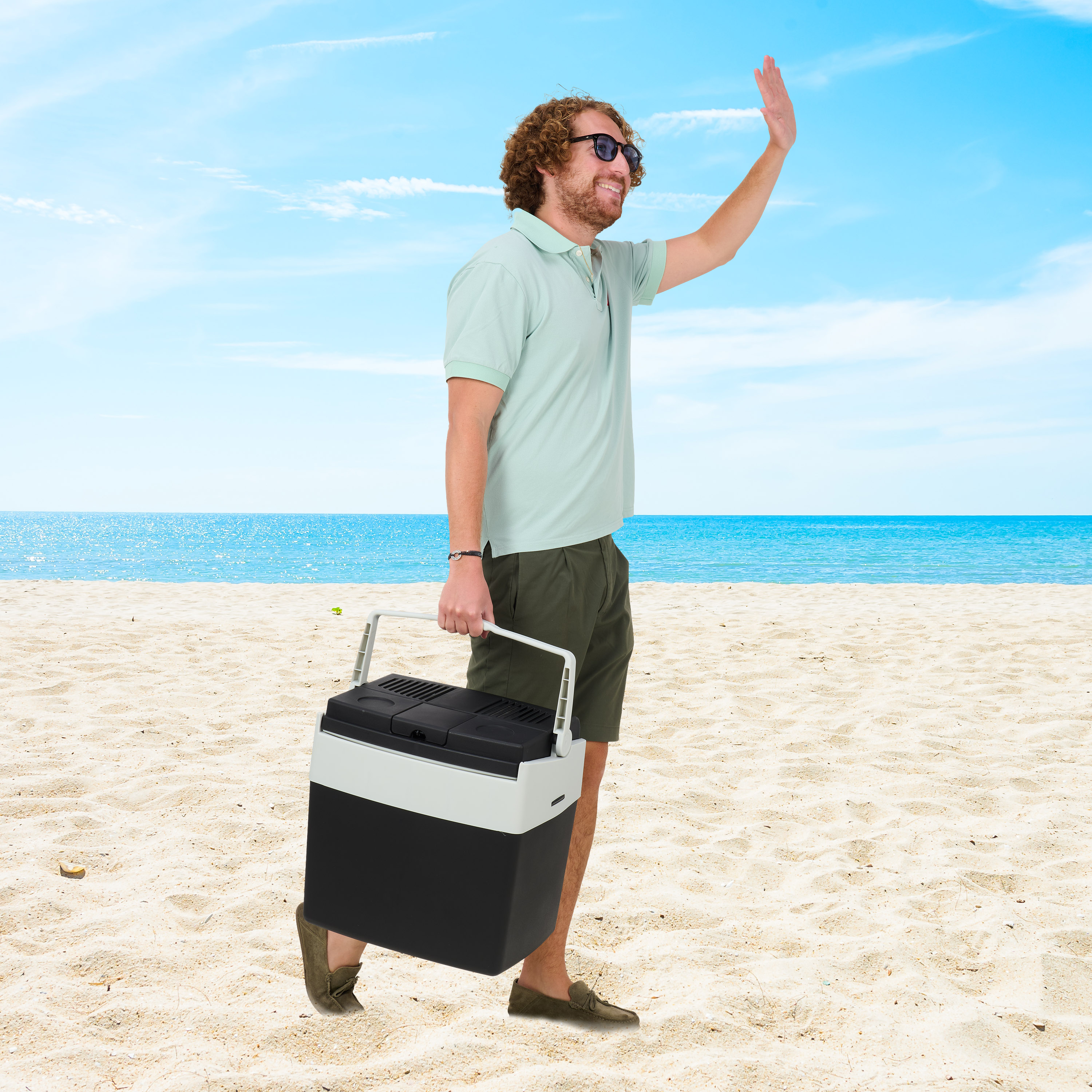 Man with cooler on beach, waving.