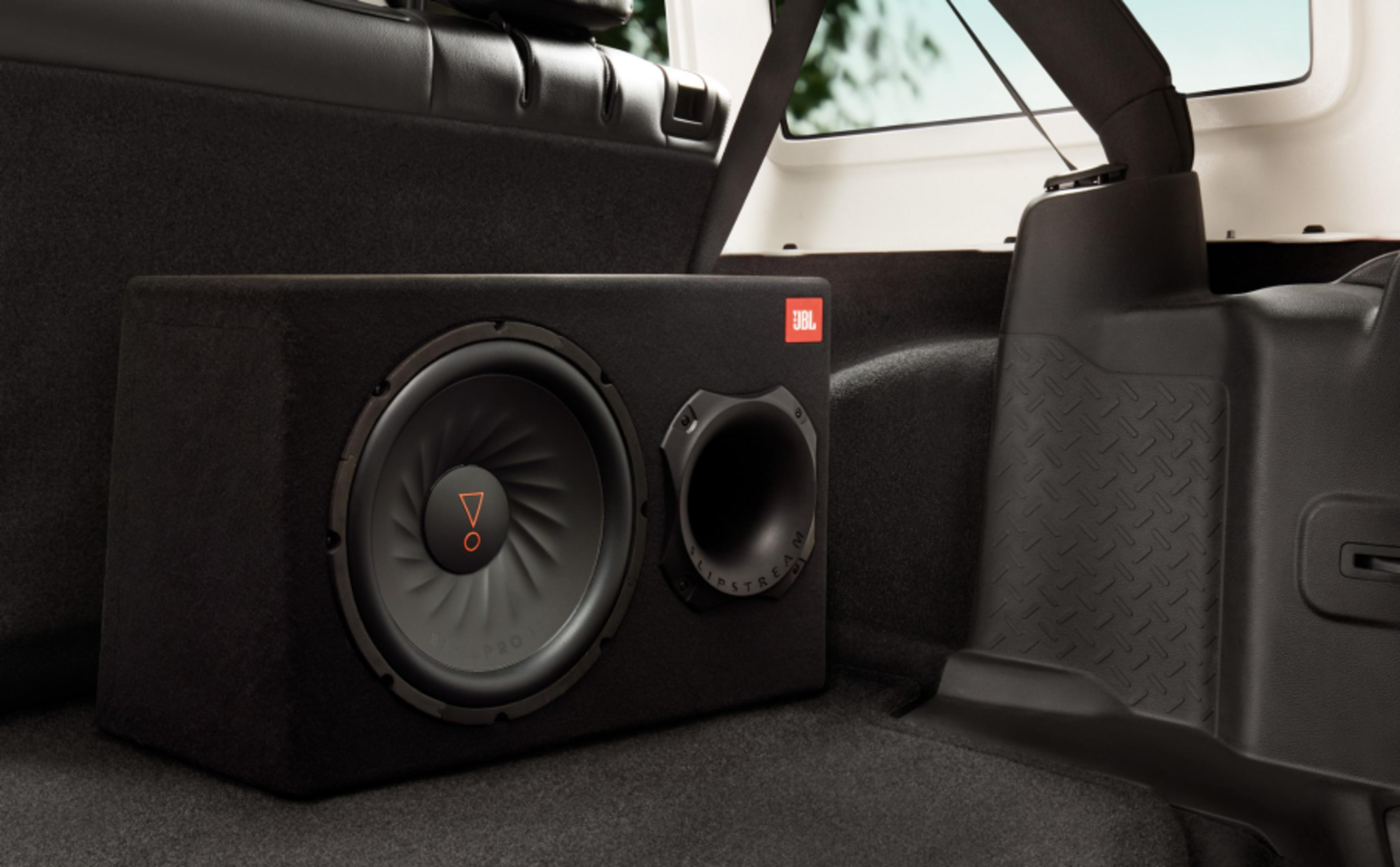 Ein schwarzer JBL Subwoofer-Kasten im Kofferraum eines Fahrzeugs.