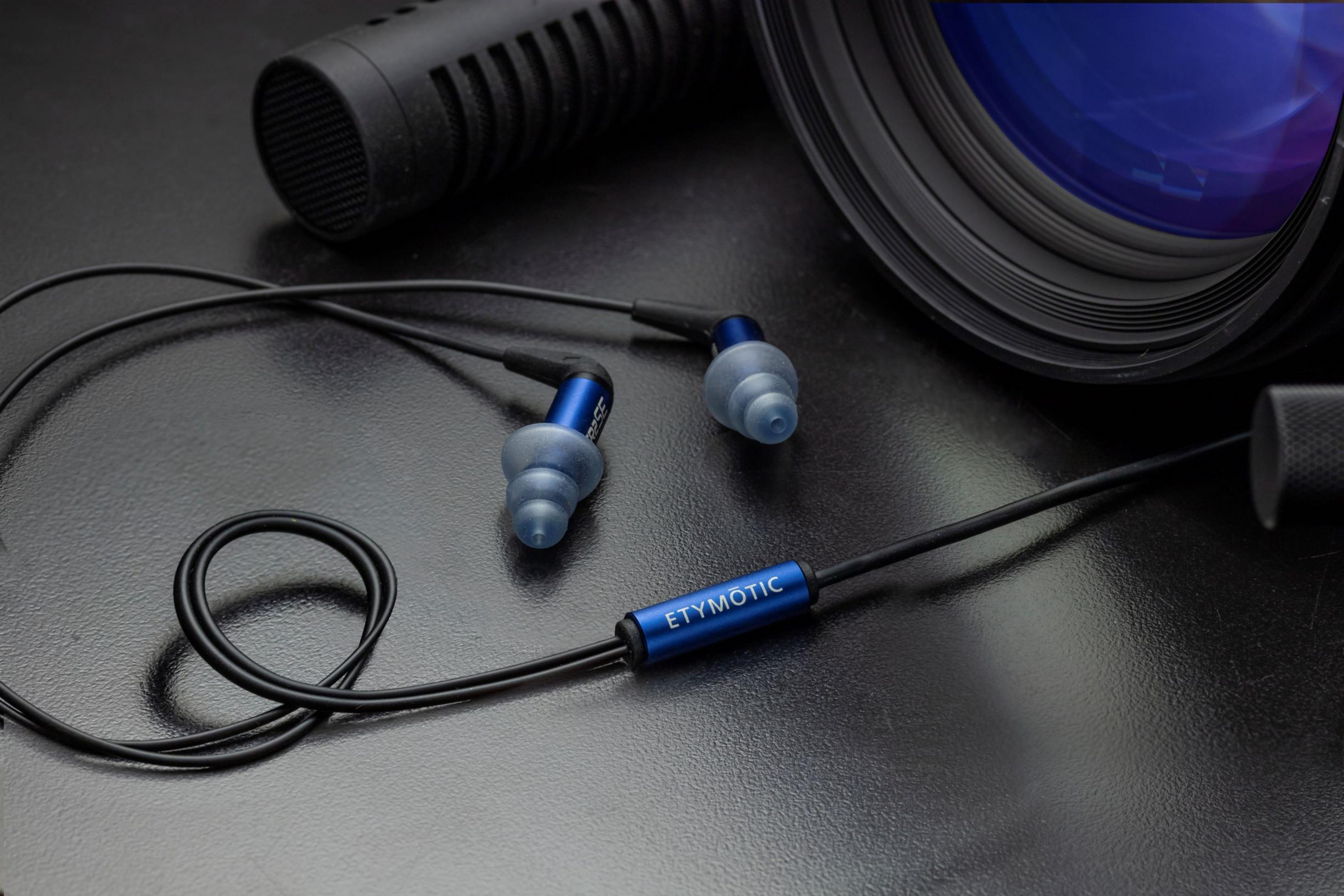 Blaue In-Ear-Kopfhörer mit schwarzem Kabel liegen auf dunklem Untergrund.