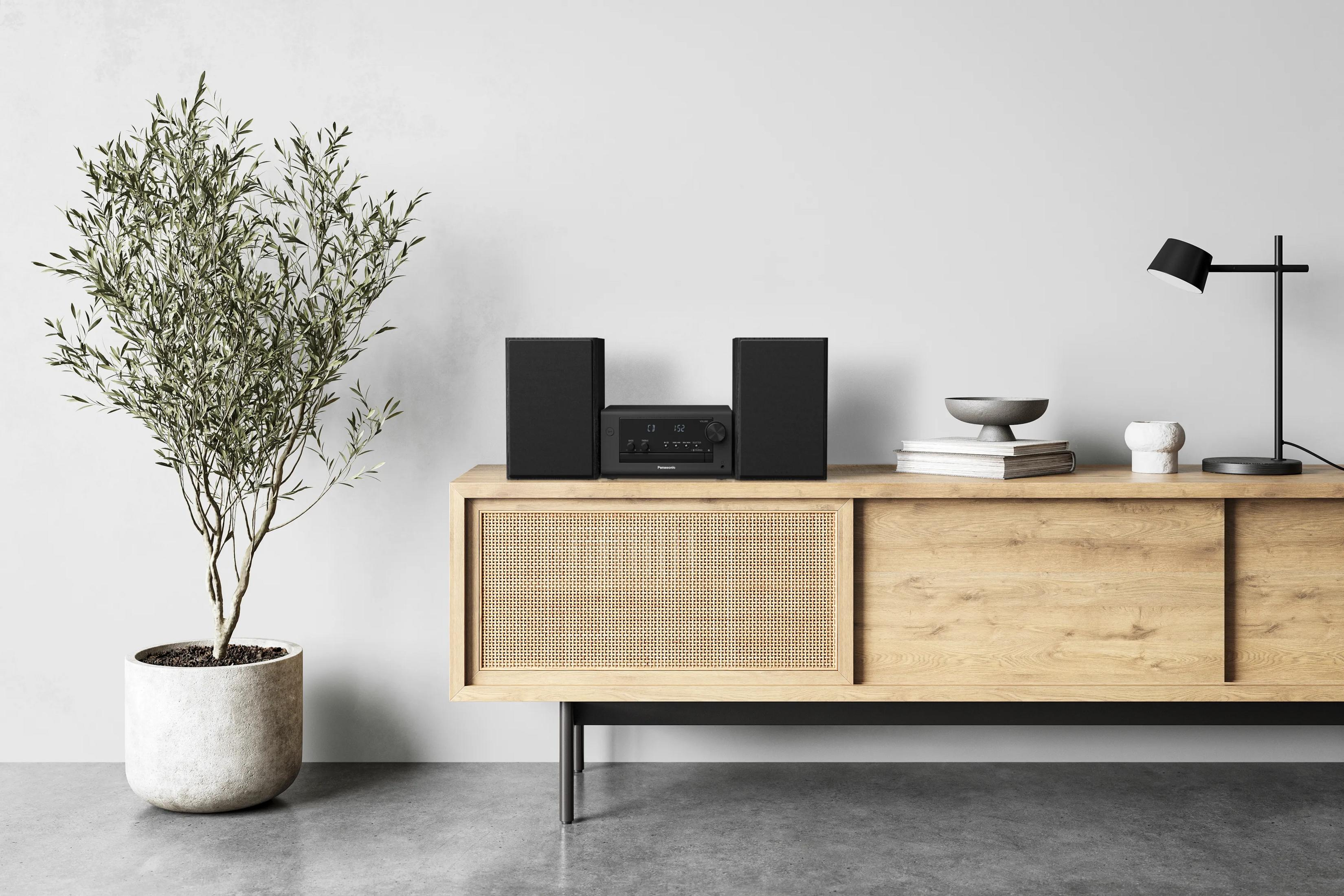Ein moderner Wohnzimmerschrank mit Stereoanlage, Lampe und Pflanze.
