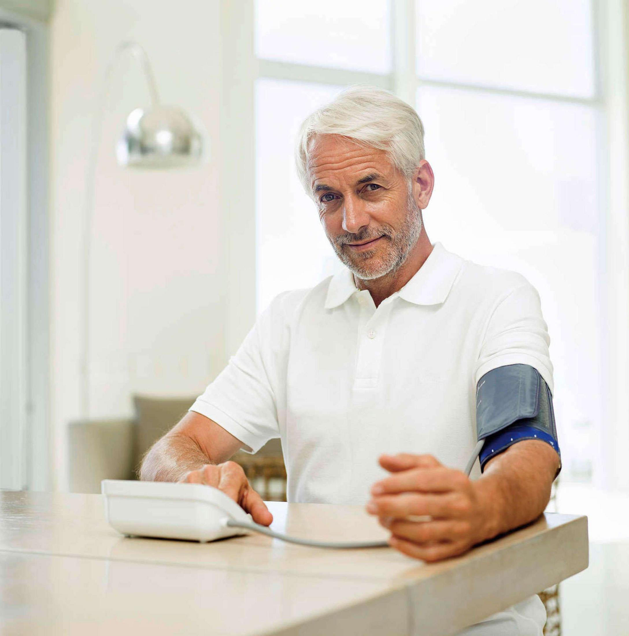 A man with a cuff on his arm and a blood pressure monitor.